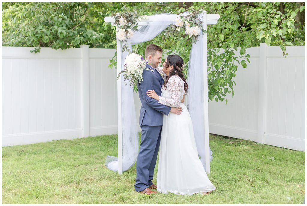 Bride and Groom stand under ceremony arch during their intimate NJ wedding ceremony captured by NJ wedding photographer Diana and Korey Photo and Film