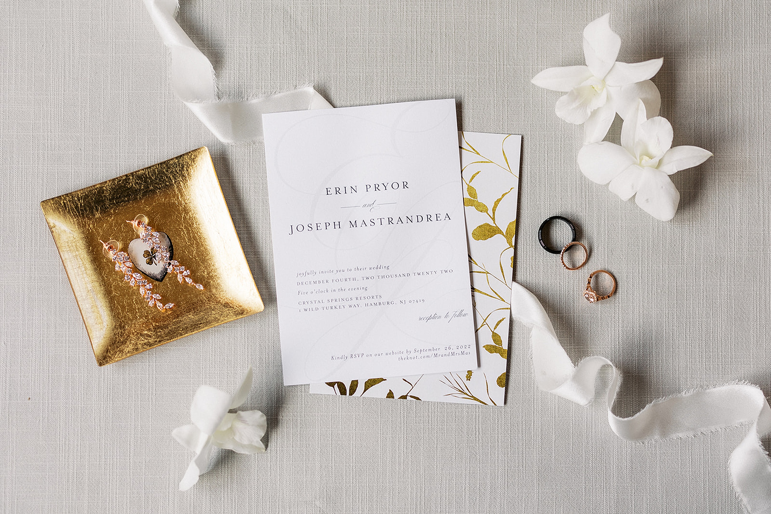 Details of wedding invitations, rings, earrings and white flowers