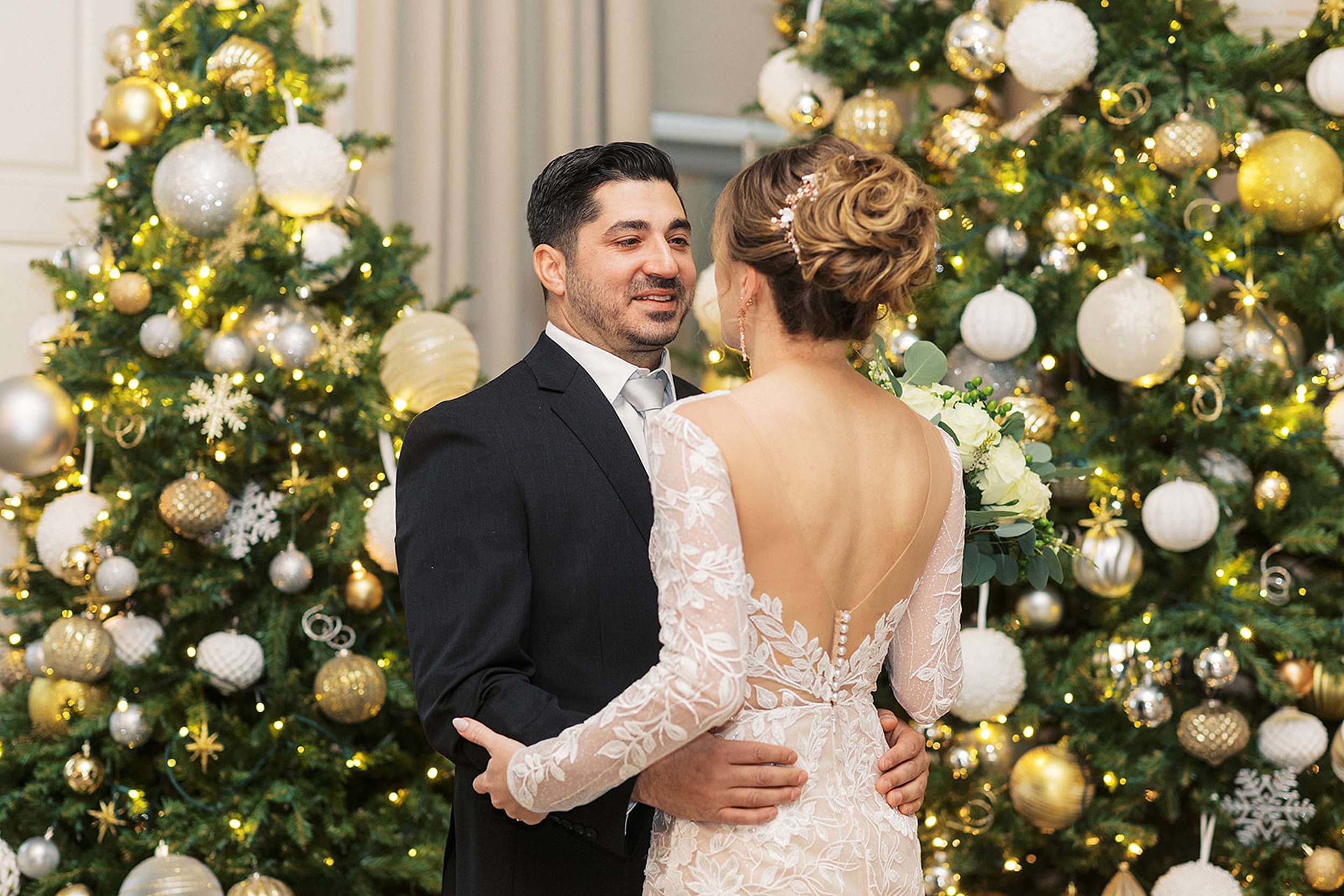 Newlyweds dance together by two large christmas trees at a Crystal Springs Wedding