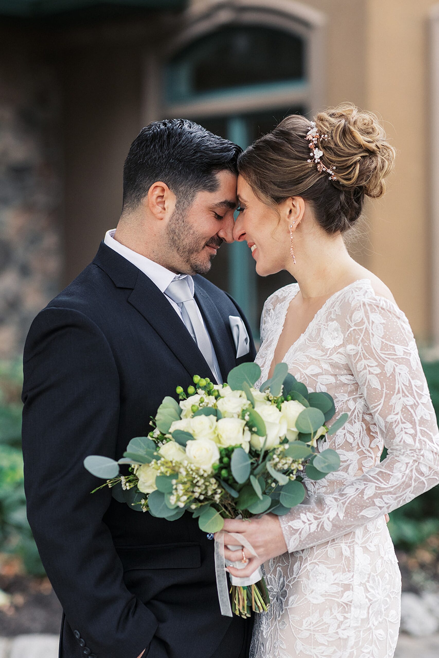 Newlyweds touch foreheads while holding a large white bouquet at a Crystal Springs Wedding