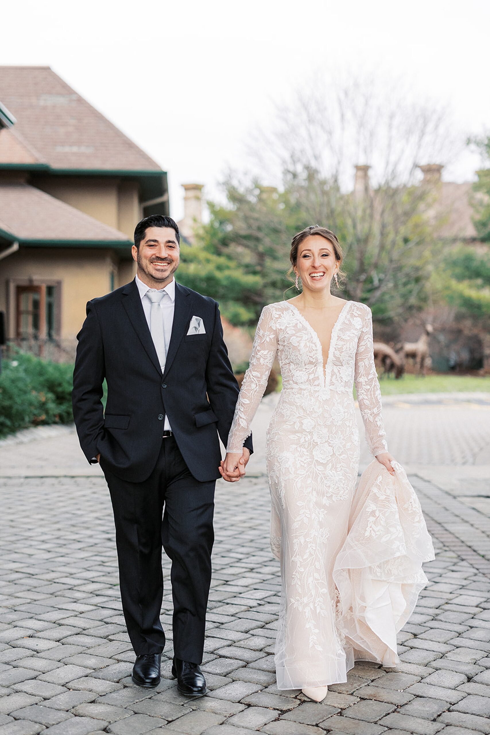 Newlyweds walk through a stone patio holding hands
