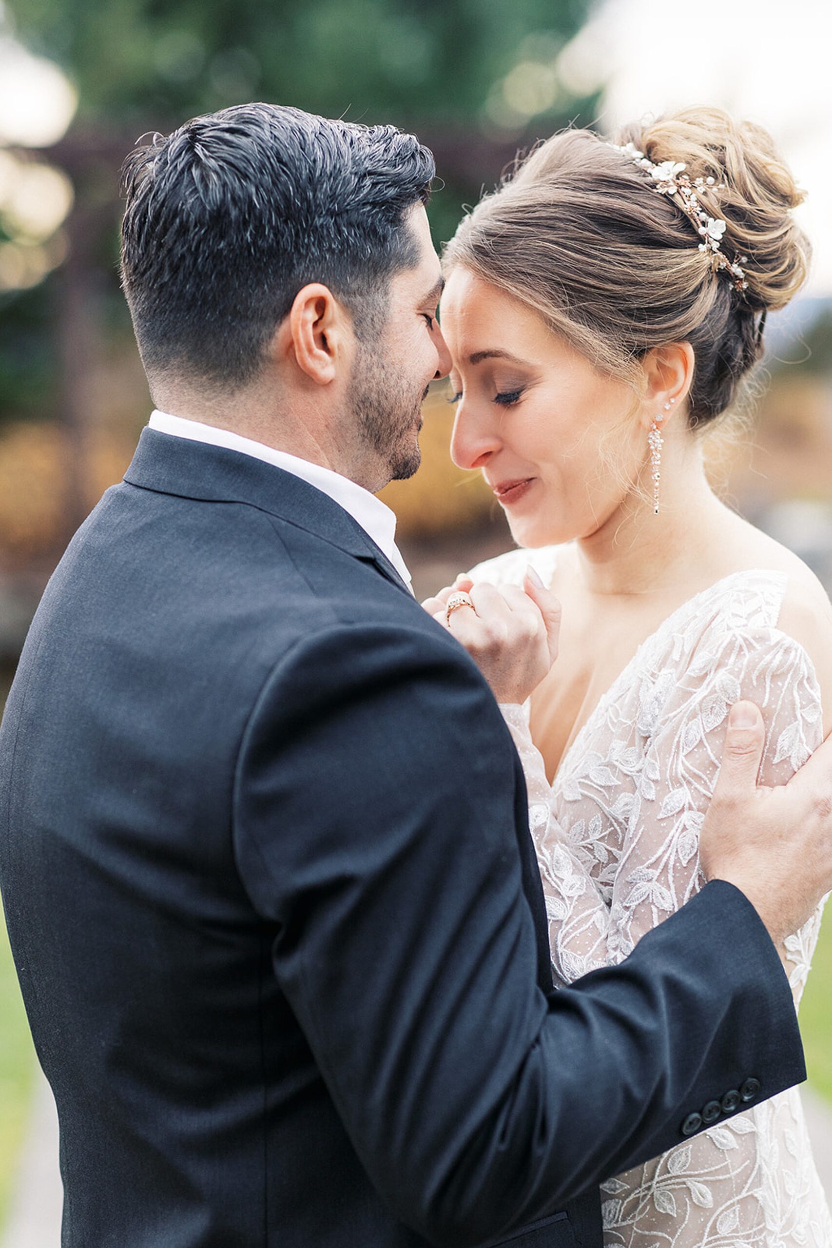 Newlyweds embrace and nuzzle while standing in a garden