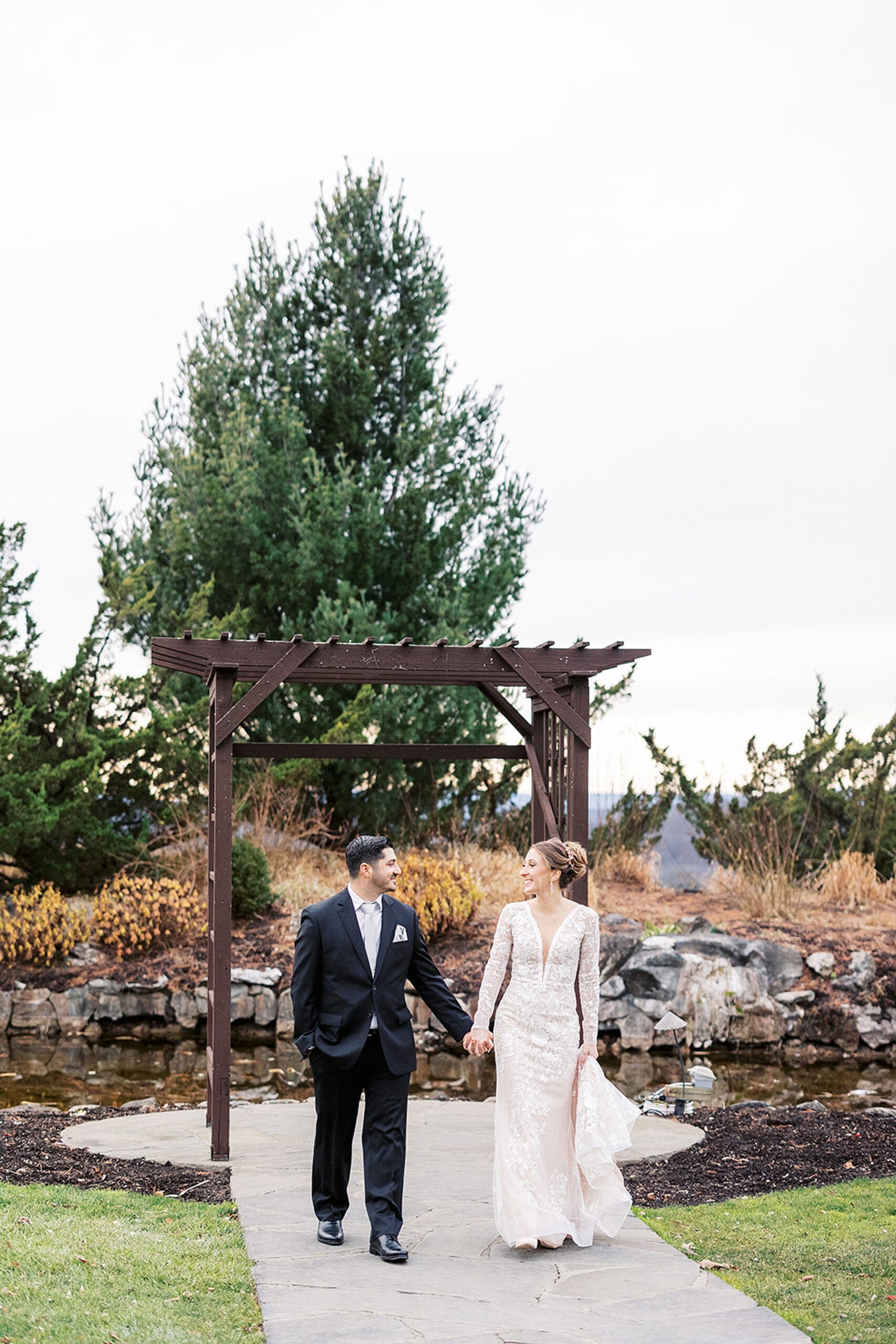 Newlyweds walk down a garden path holding hands at a Crystal Springs Wedding