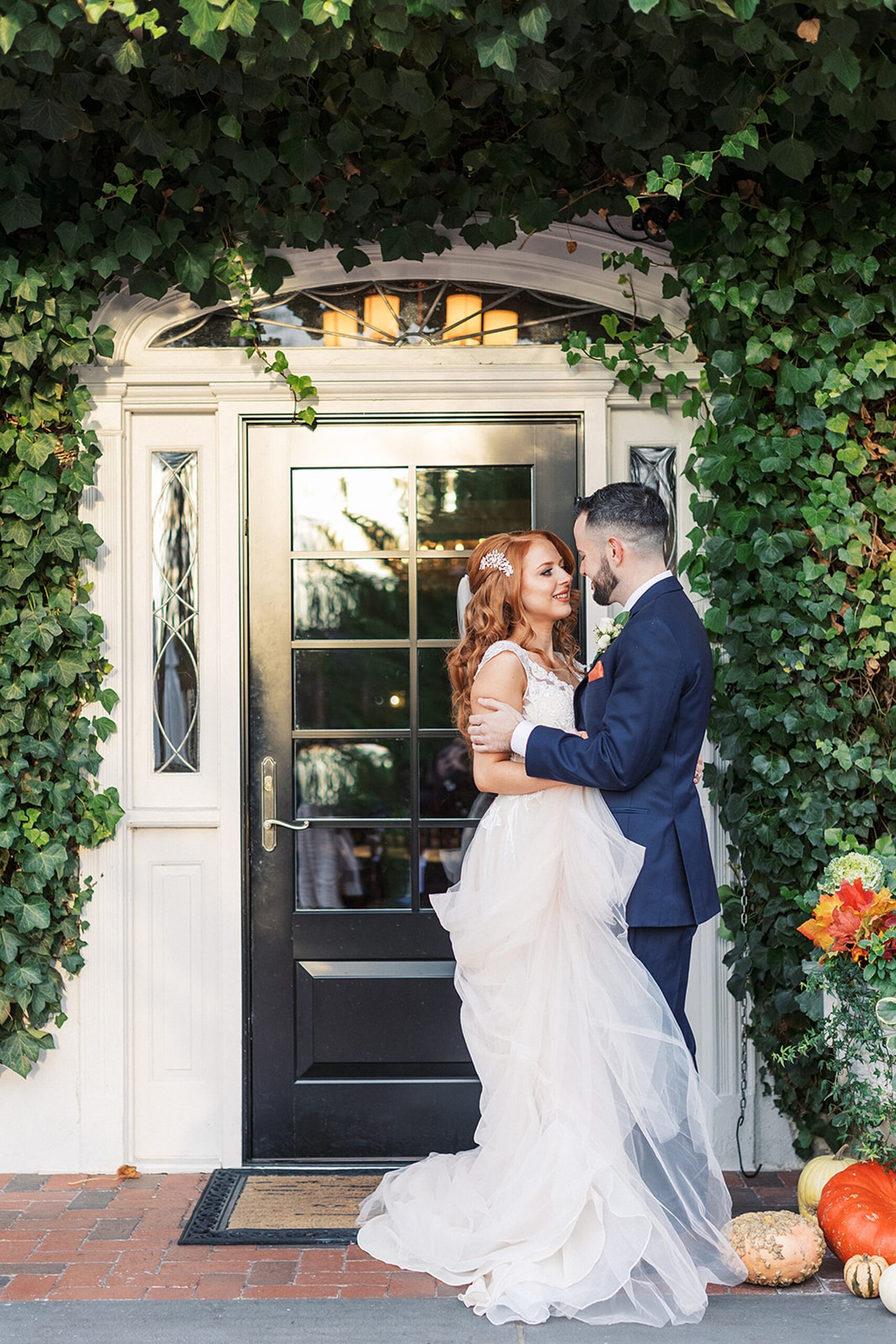 Newlyweds embrace for a kiss under an ivy covered front door entrance at a David's country inn wedding