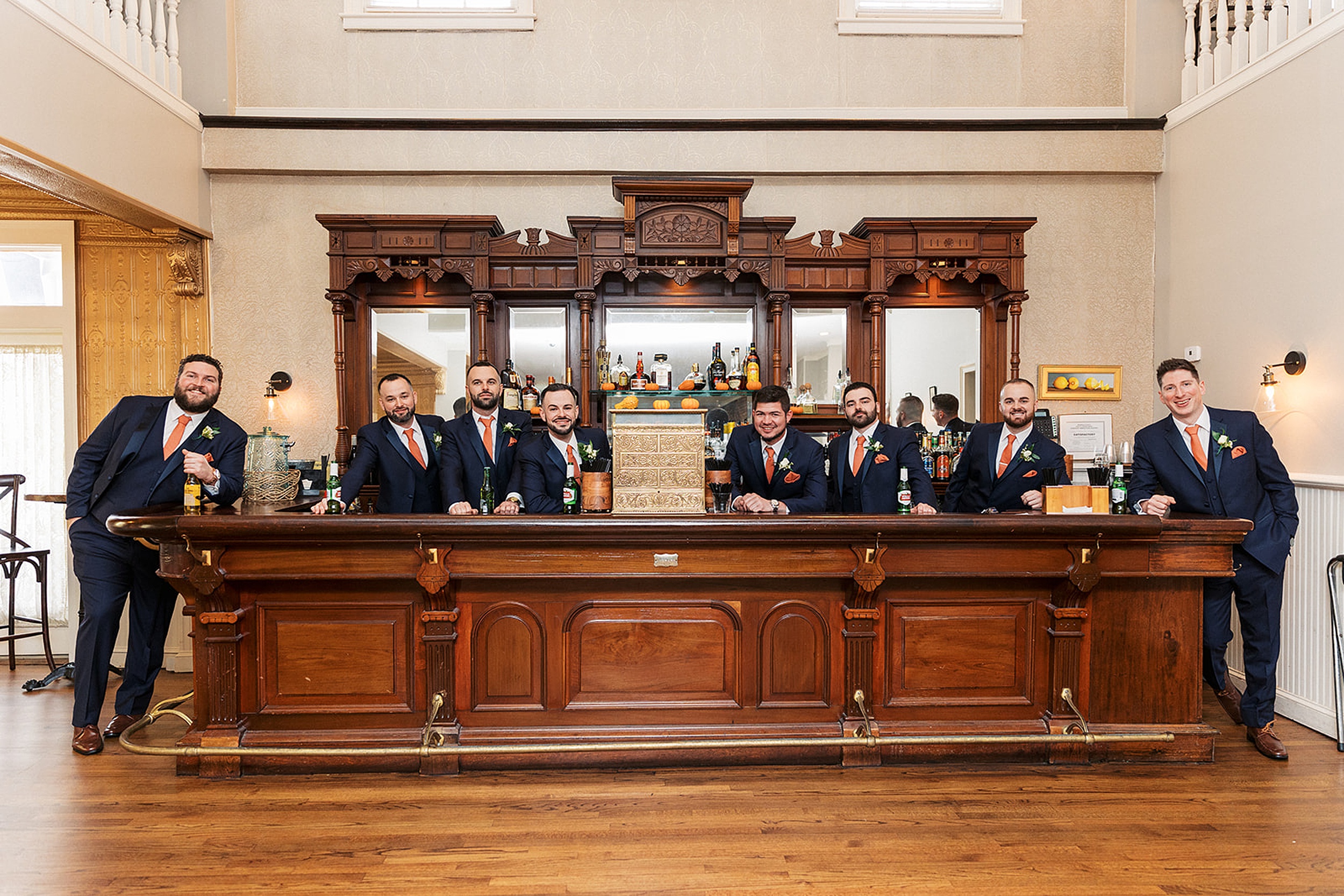 A groom and his groomsmen lean on an antique bar together at a David's country inn wedding