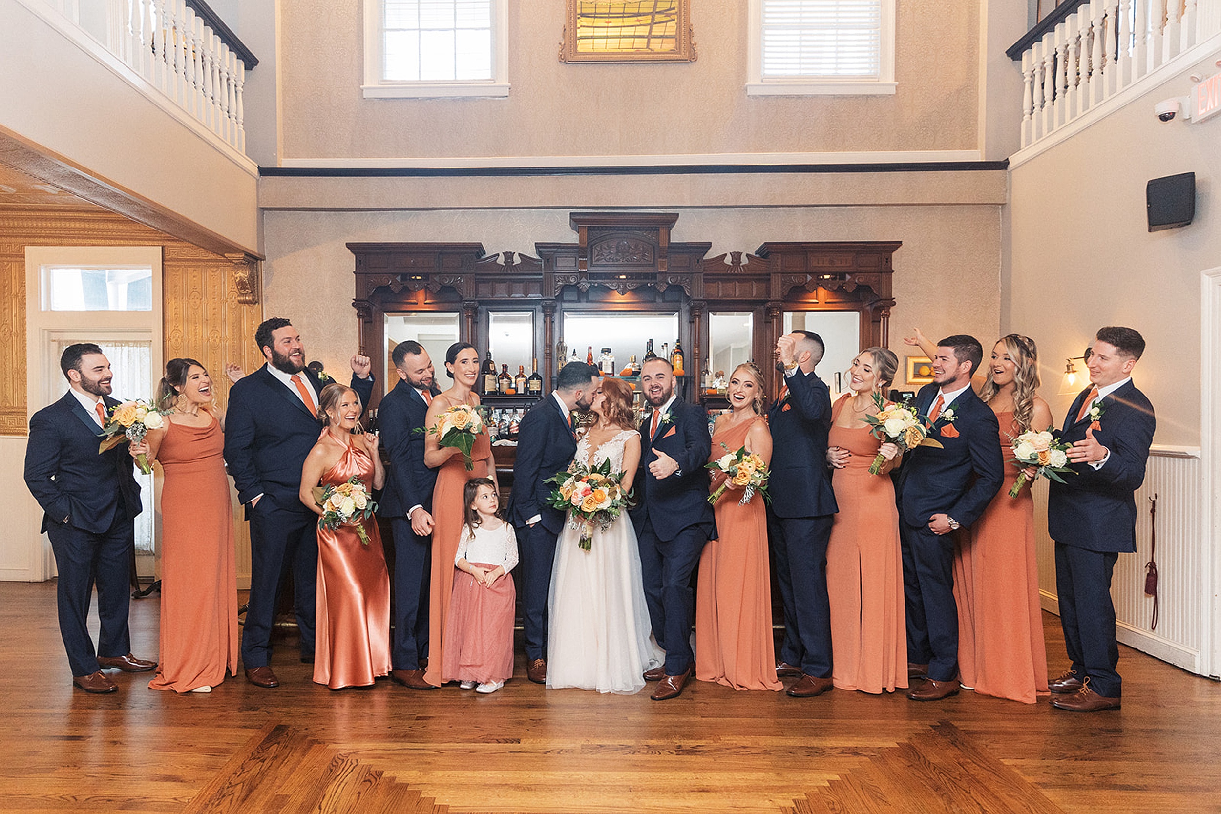 Newlyweds kiss in front of a bar with their wedding party cheering them on surrounding them at a David's country inn wedding