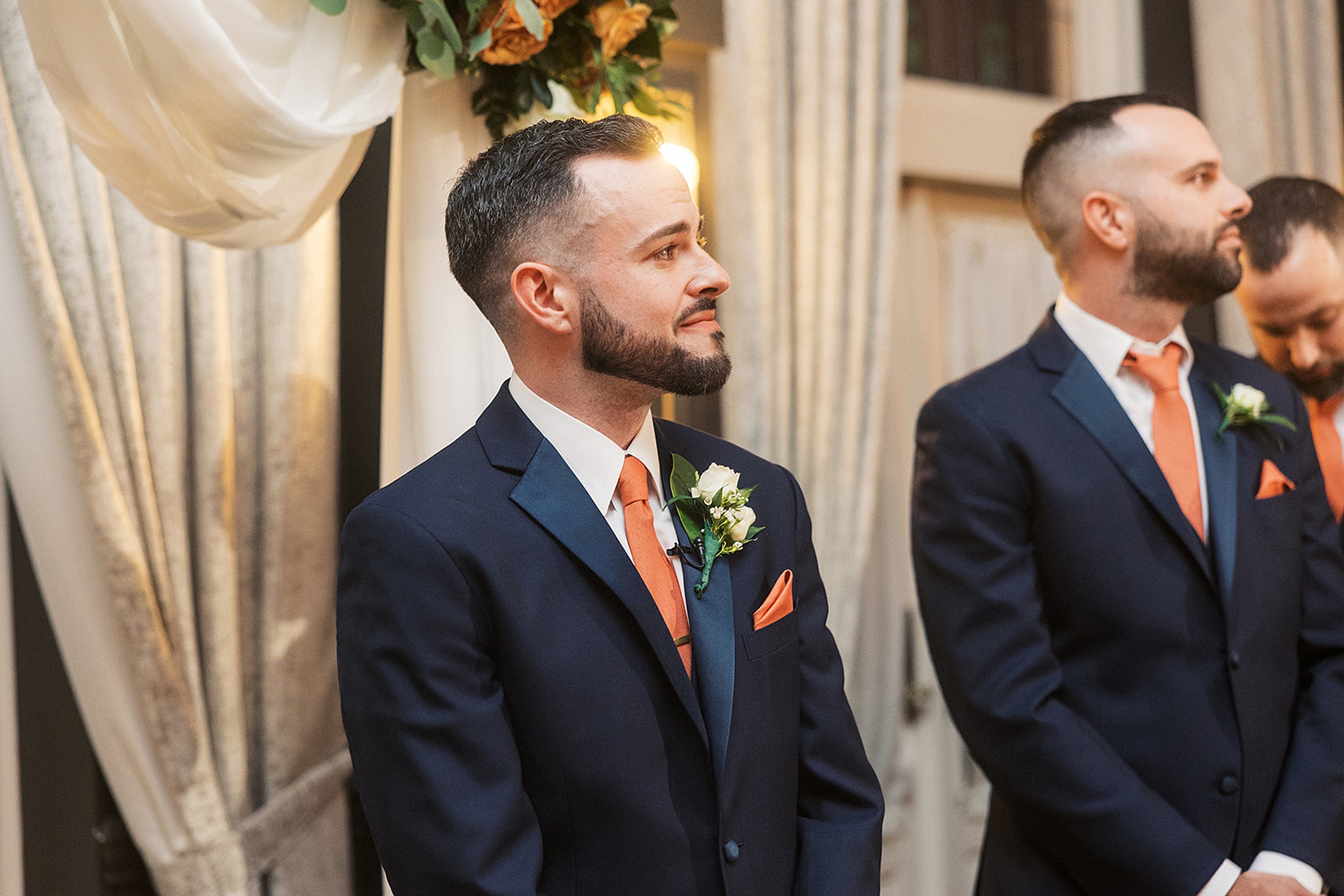 A groom looks out over the guests to his bride entering the ceremony