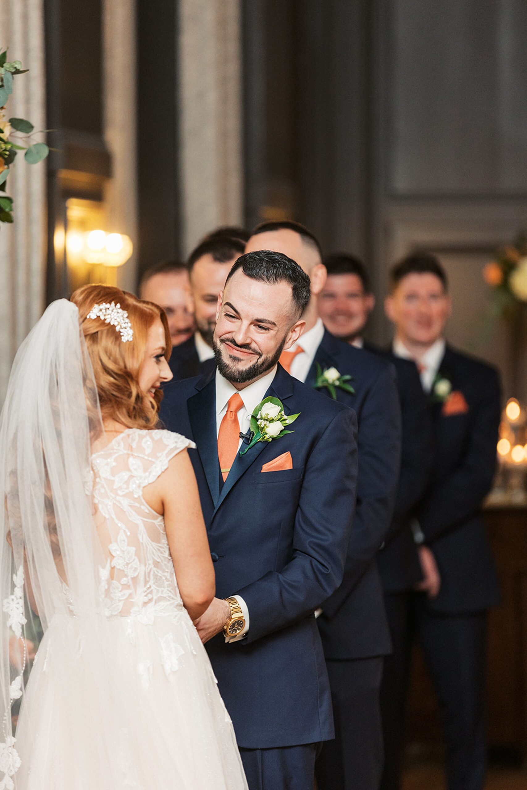 Newlyweds smile at their ceremony with the groomsmen behind them