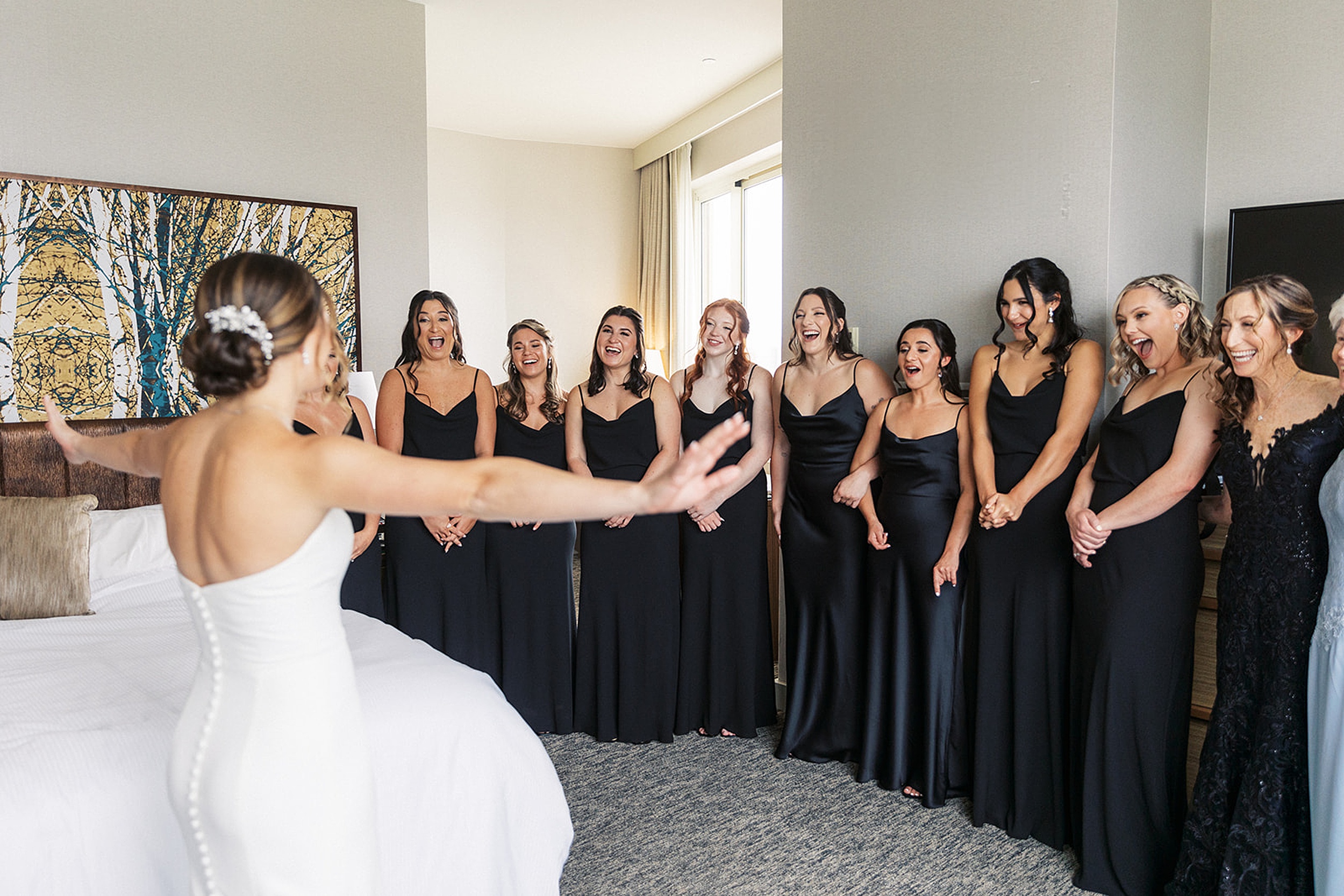 A bride reveals her dress to her bridal party in a hotel room for a Hudson House wedding