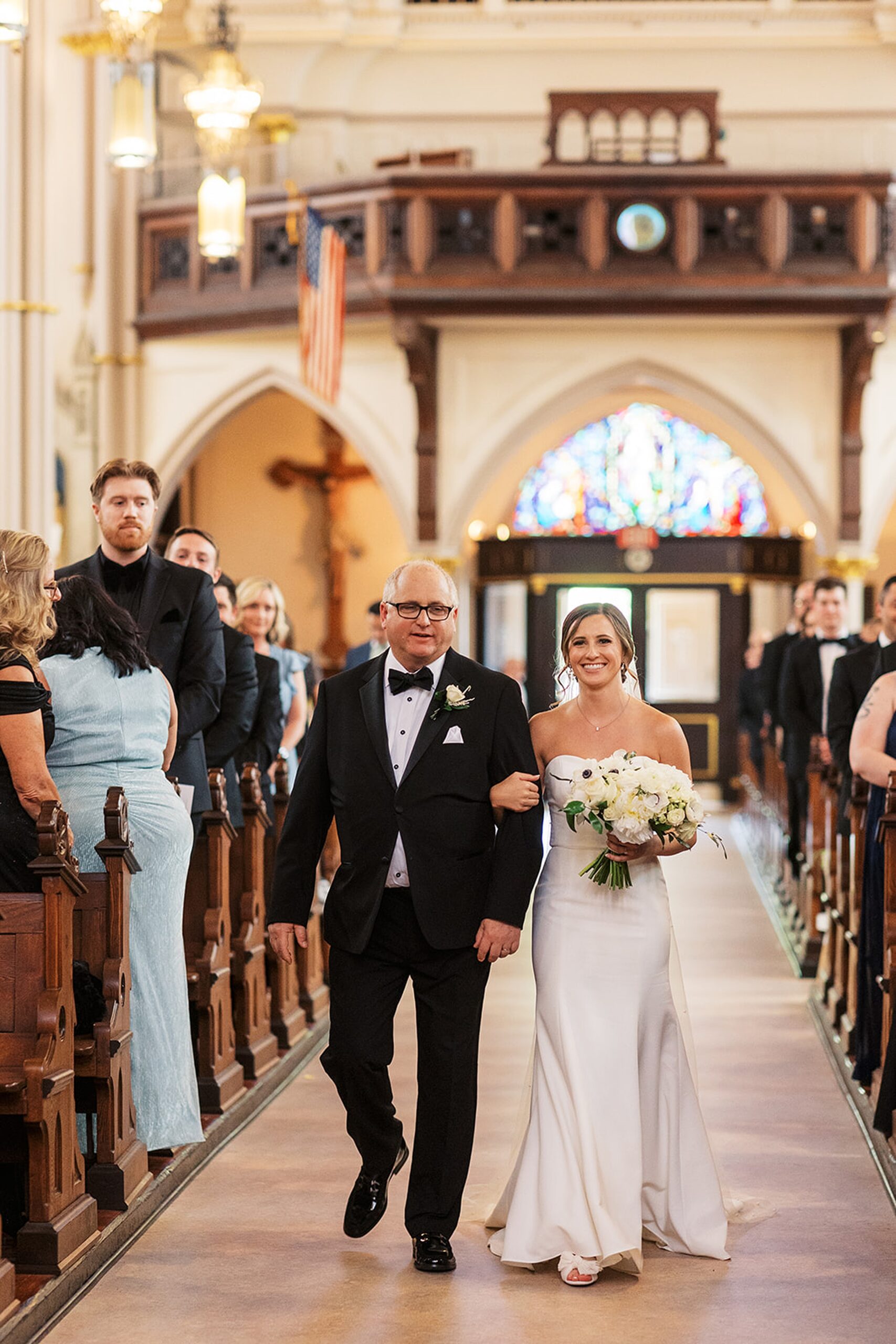 A father walks his daughter down the aisle of a church for her wedding