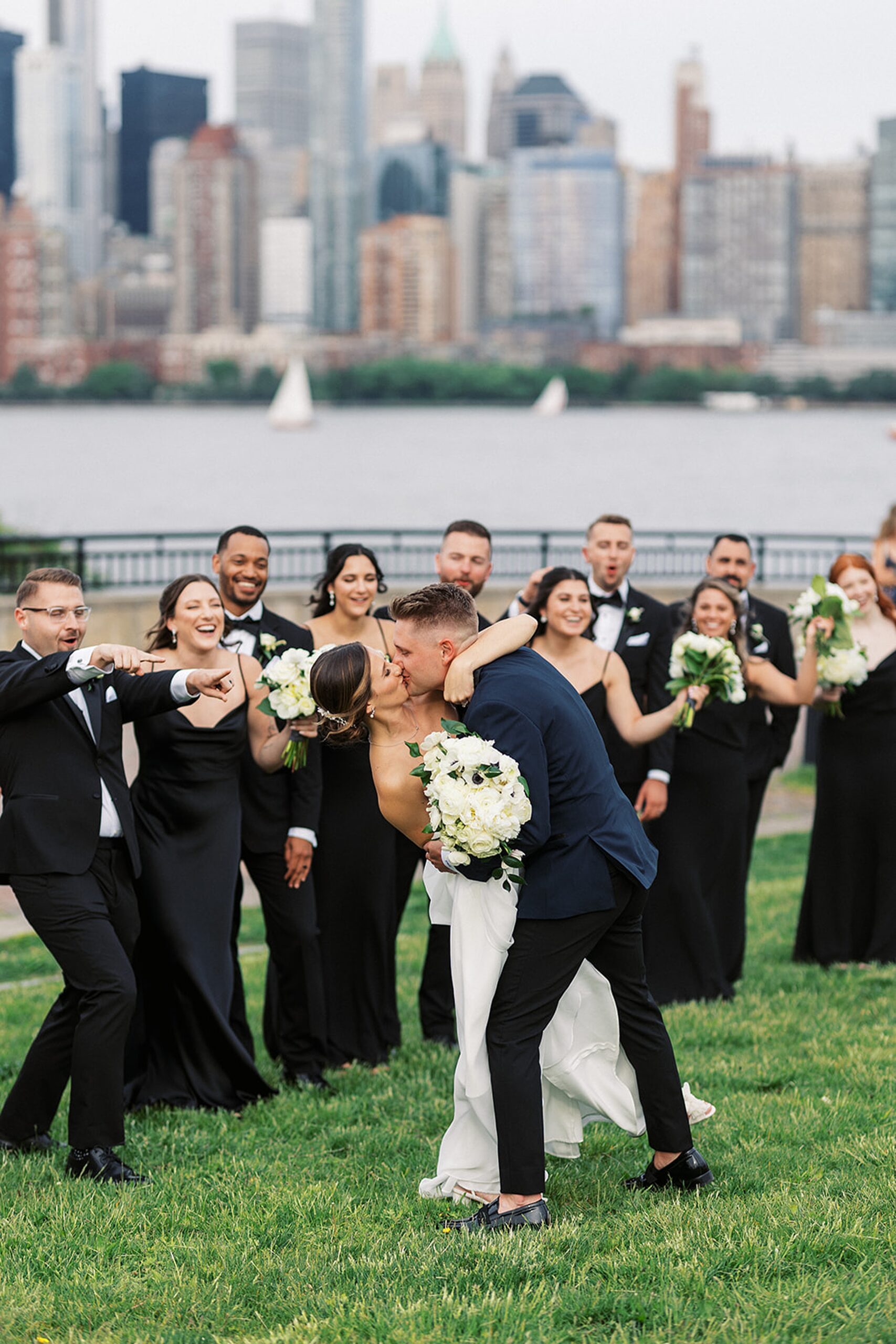 Newlyweds kiss and dip while being cheered for by their large wedding party