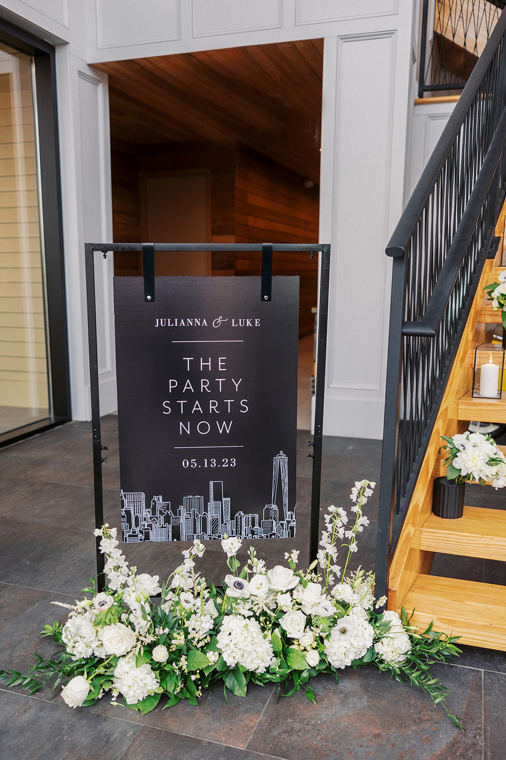 Details of a wedding reception entrance decorated with a sign and white flowers