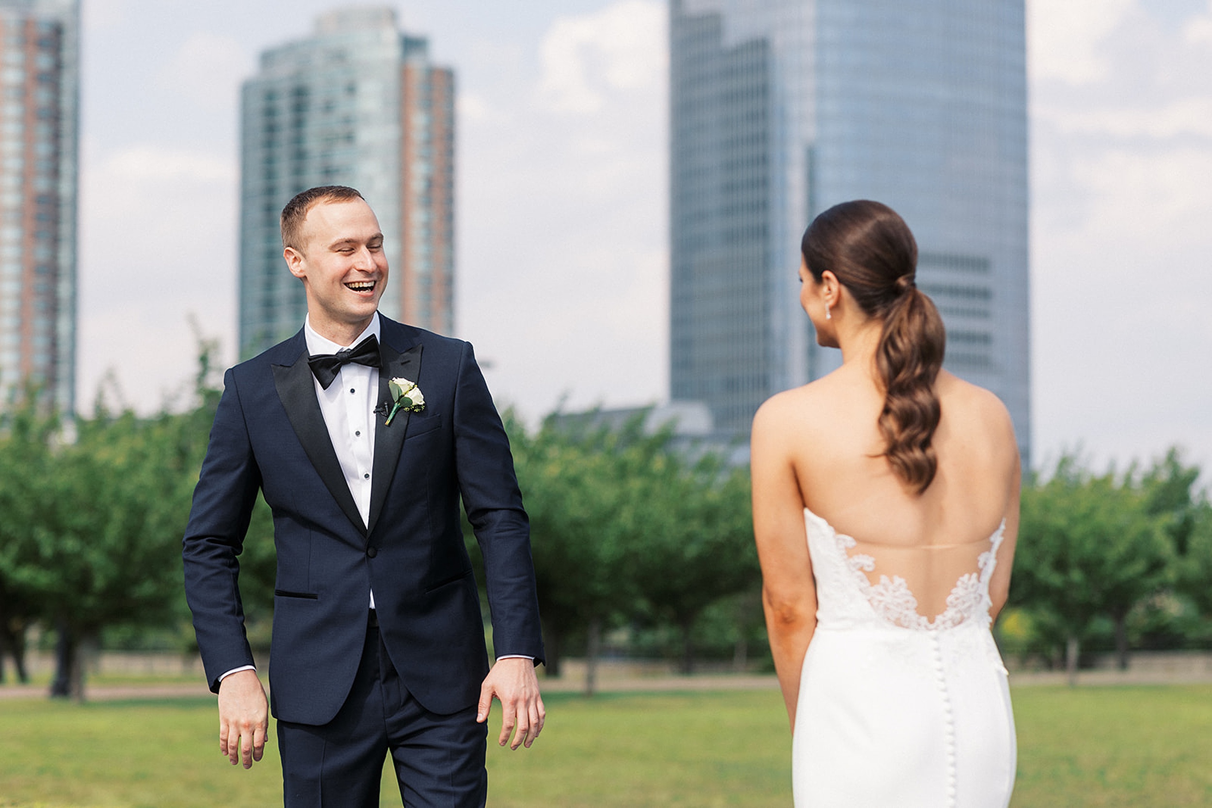 A groom smiles as he sees his bride in her while lace dress for the first time