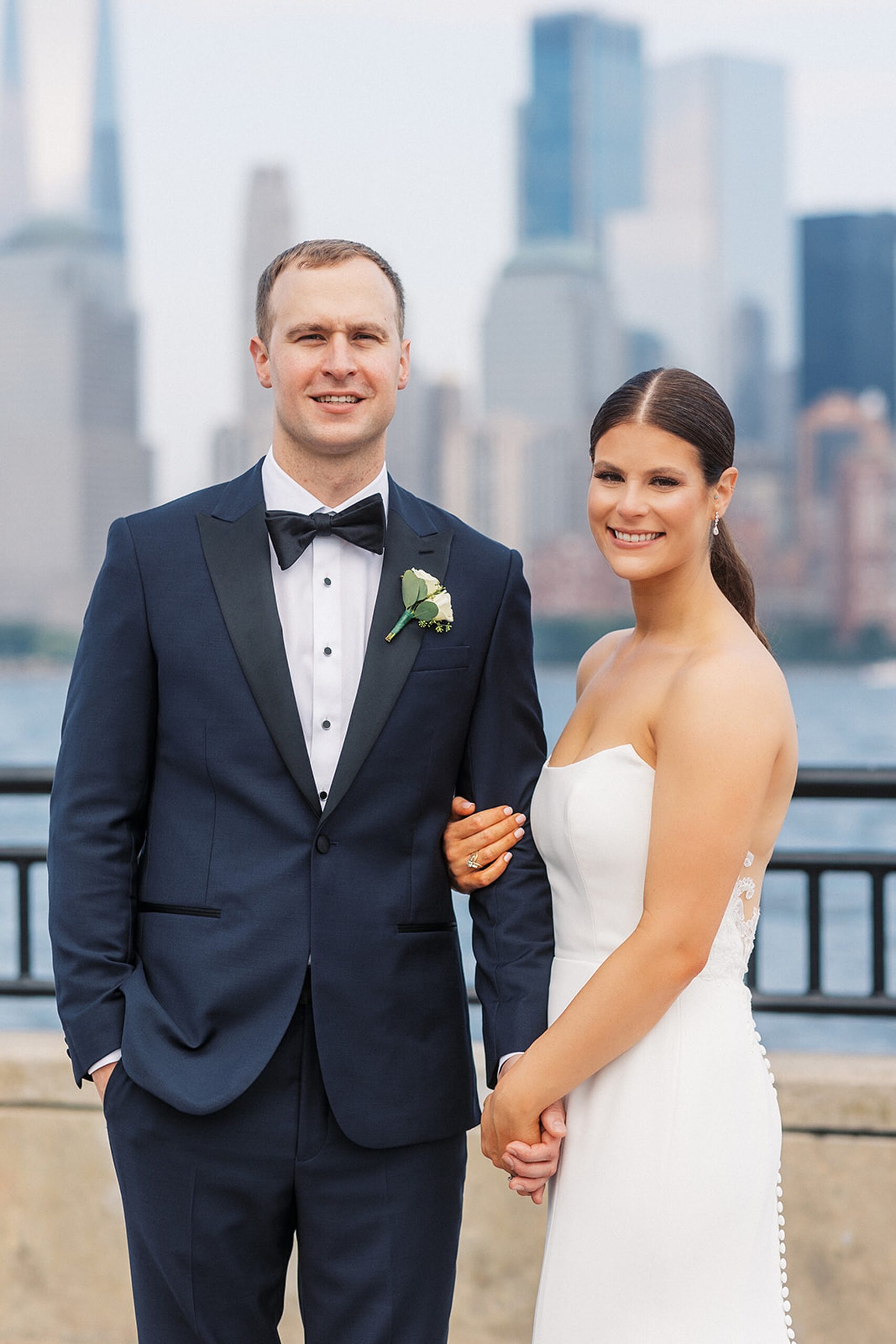 Newlyweds hold hands while standing in a riverfront park for their Liberty House Wedding
