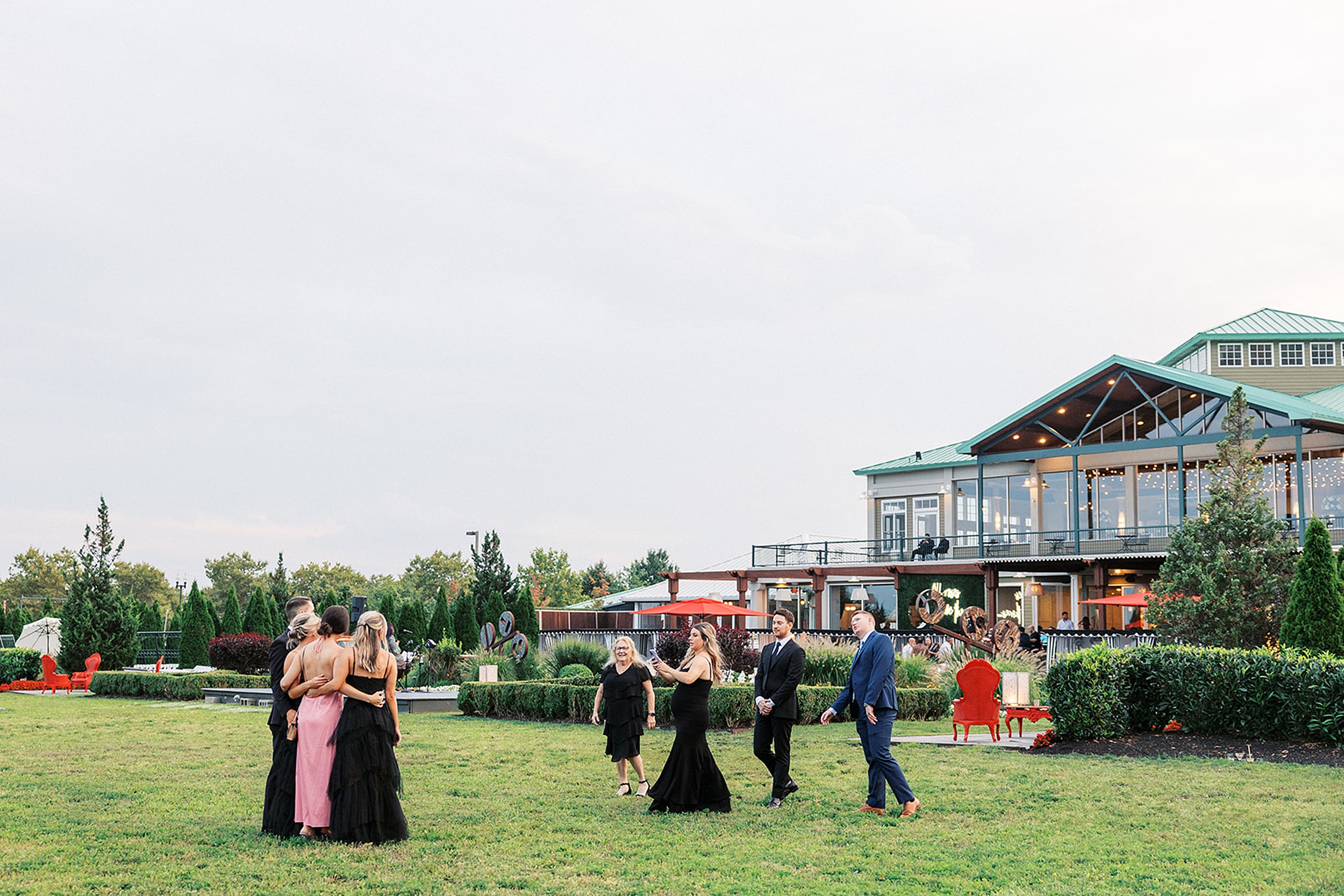 Wedding guests take pictures in a grass field behind the Liberty House Wedding venue
