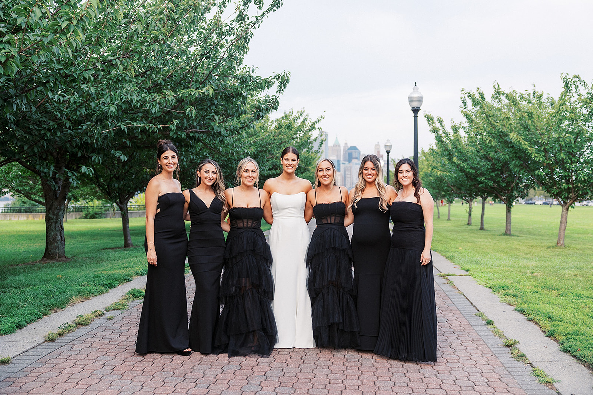 A bride stands with her six bridesmaids all in black dresses