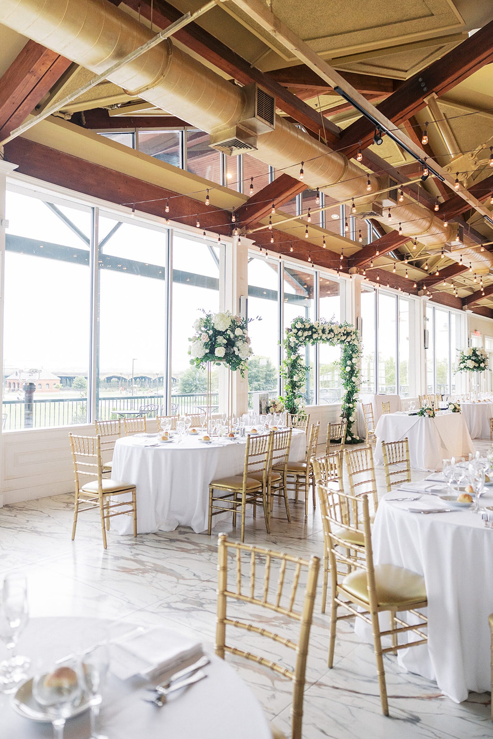 Details of a wedding reception setup with white florals and linens paired with golden chairs at the Liberty House Wedding venue