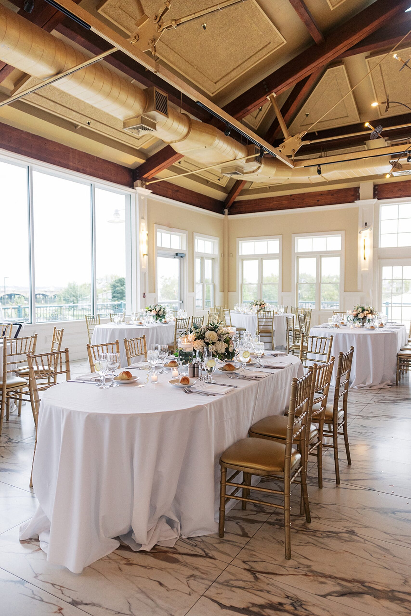 Details of a wedding reception setup up with white linens and gold chairs