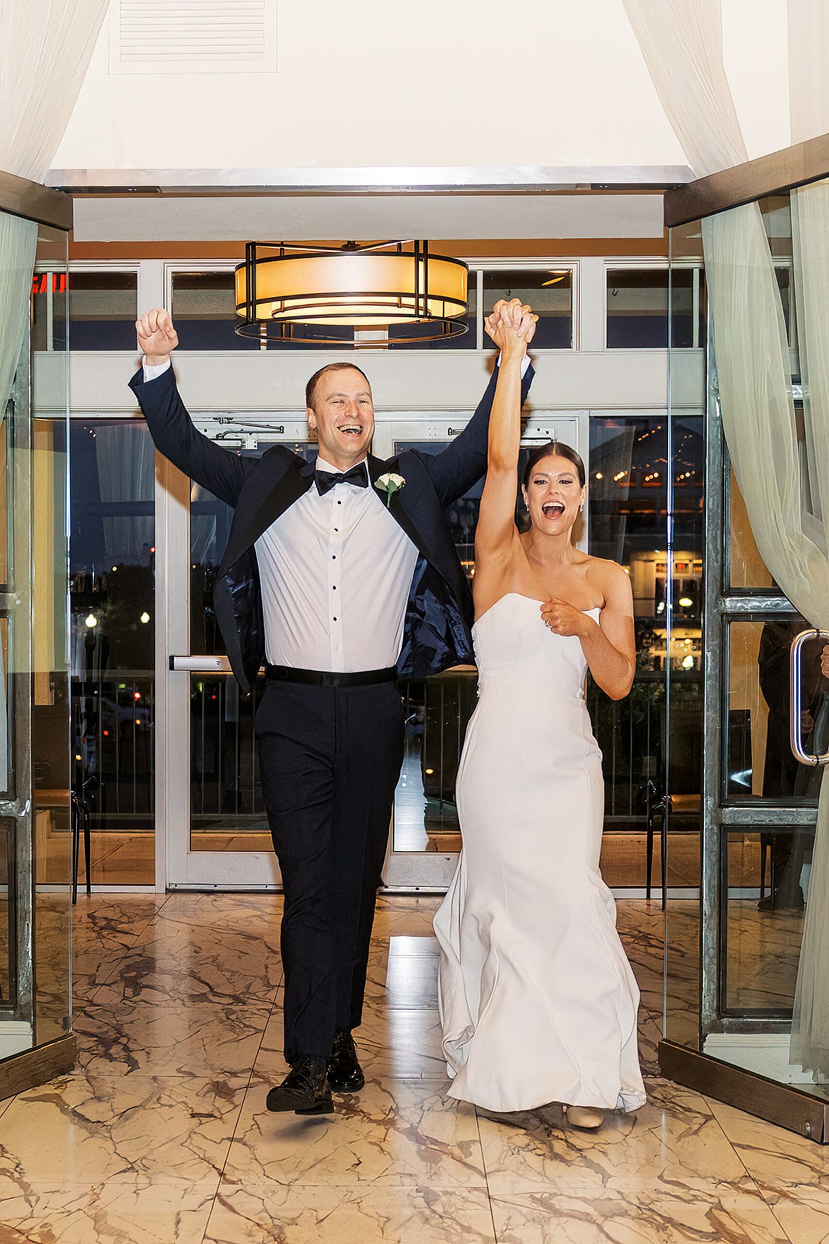 Newlyweds cheer with hands up as they enter their Liberty House Wedding reception