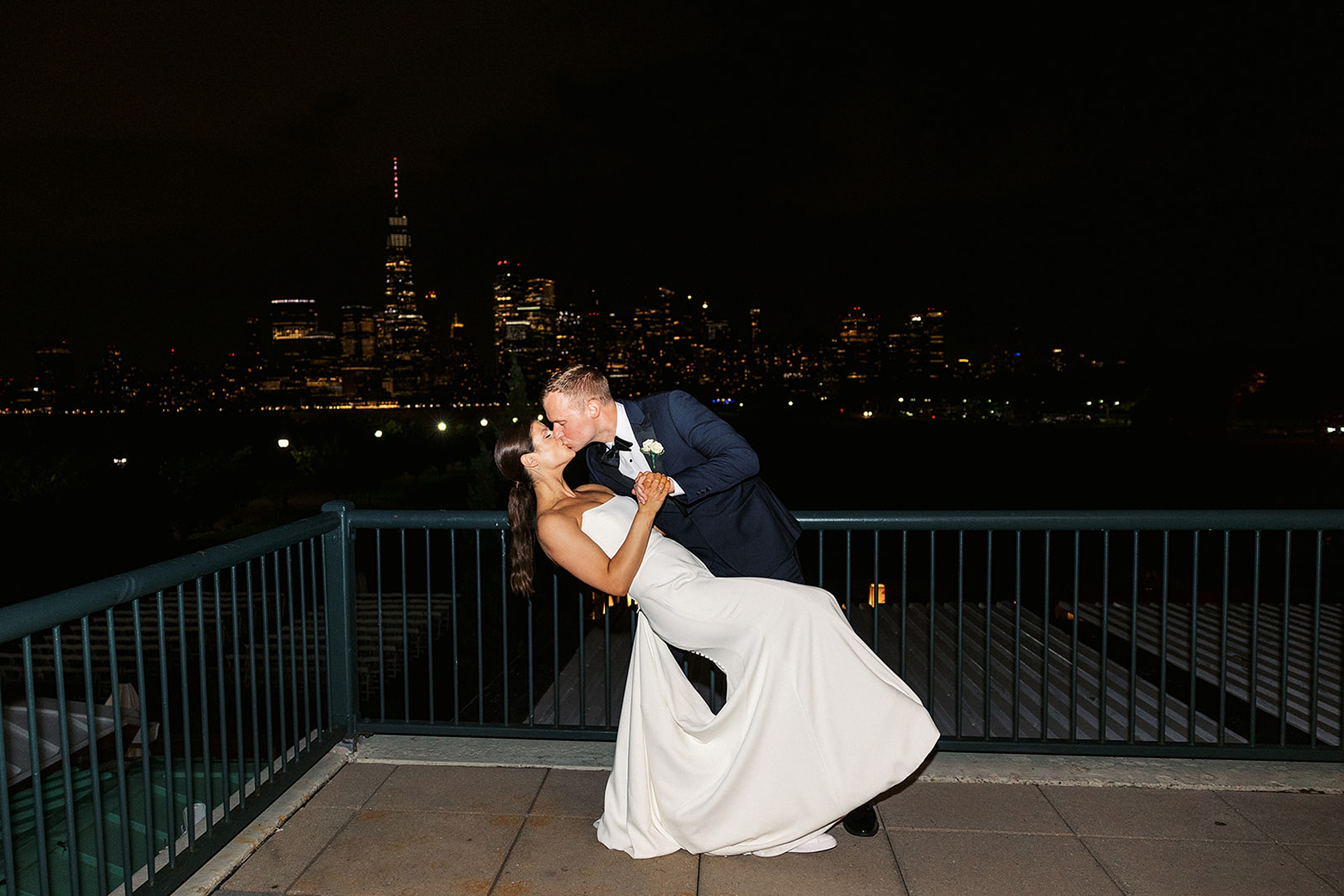 A groom dips and kisses his bride on a riverfront patio at their Liberty House Wedding