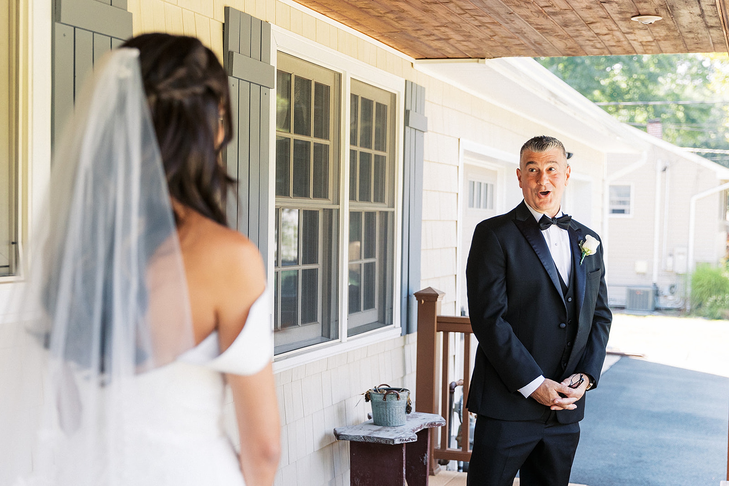 A father sees his daughter in her wedding dress for the first time on a porch