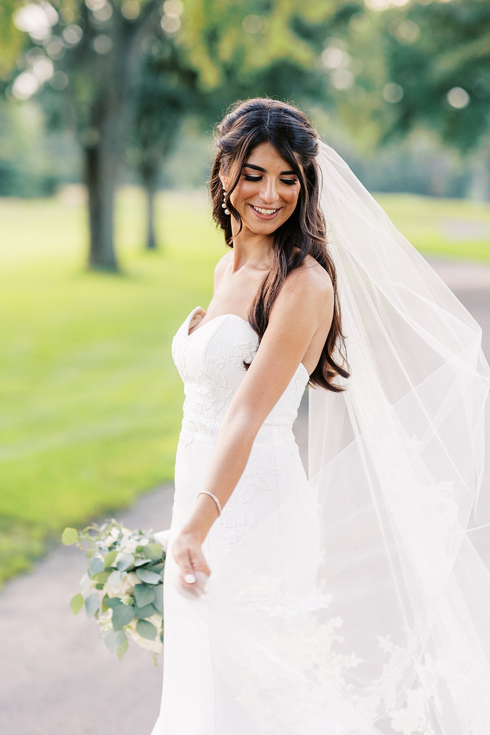 A bride twirls and dances in a paved golf cart path on a golf course