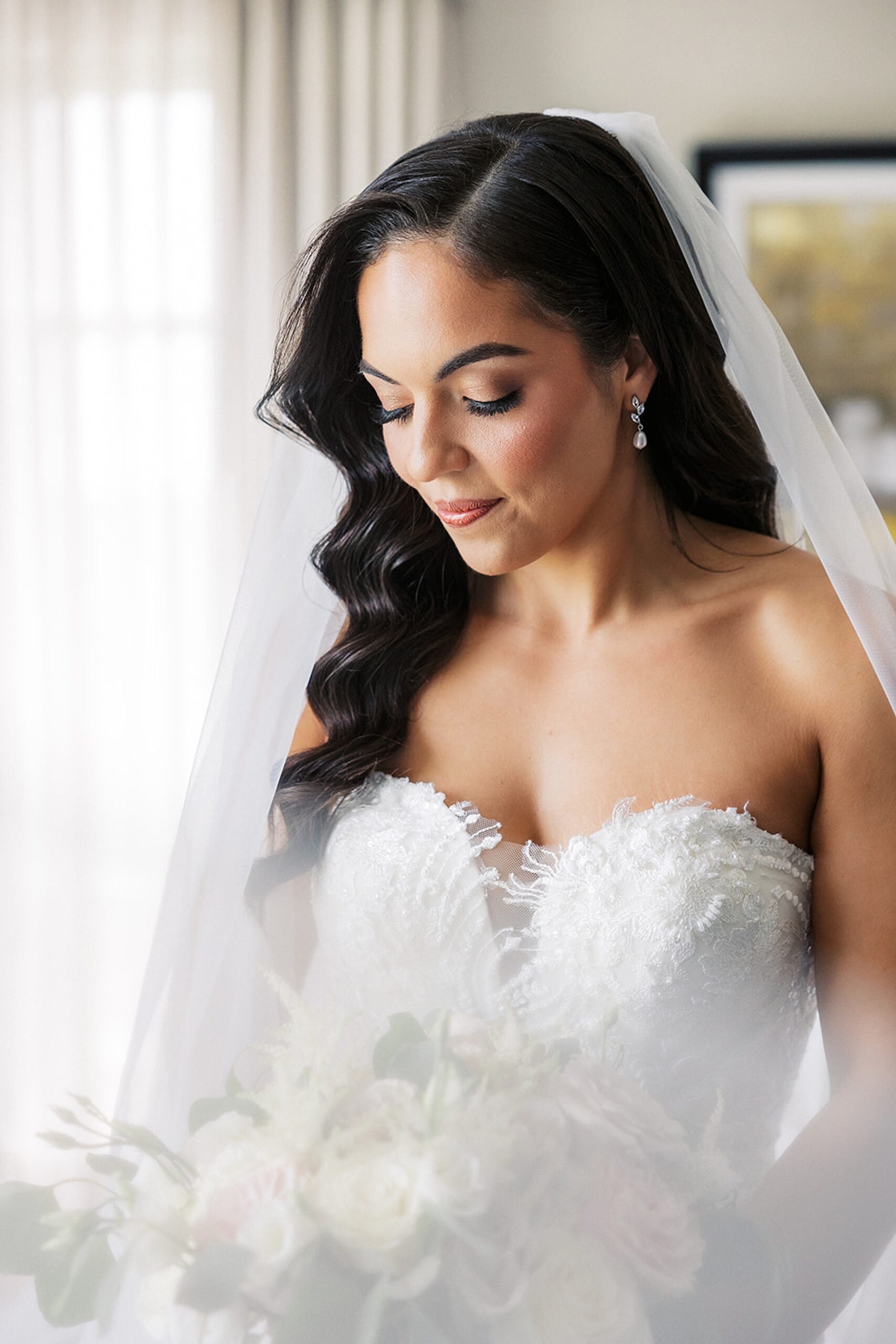 A bride gazes down at her bouquet while getting ready
