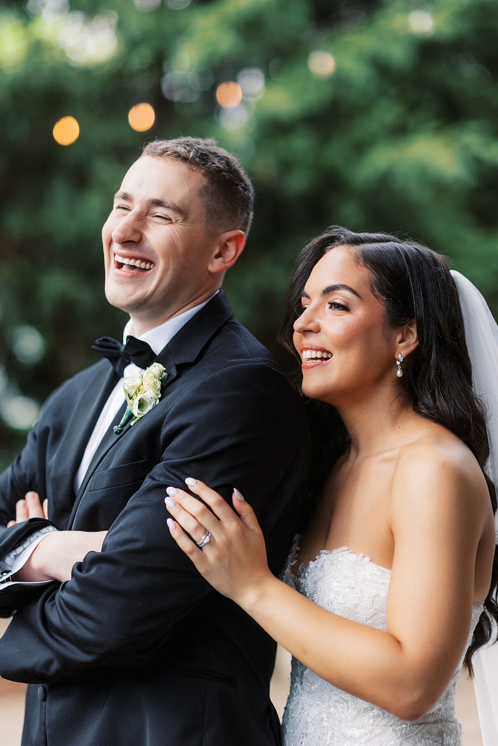 A bride holds onto the arm of her husband while laughing outside at a Stonehouse At Stirling Ridge Wedding