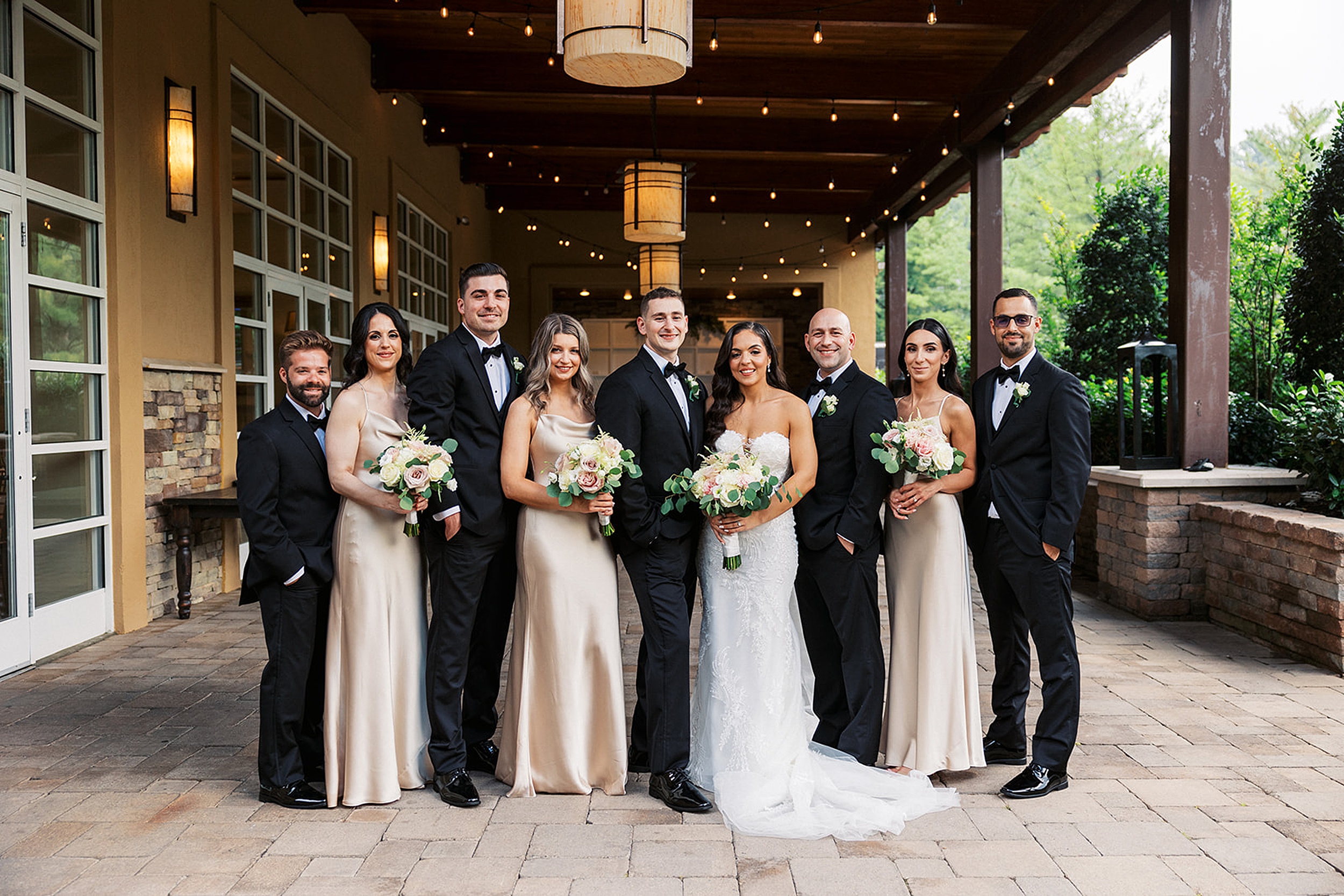 Newlyweds stand in a garden patio with their wedding party