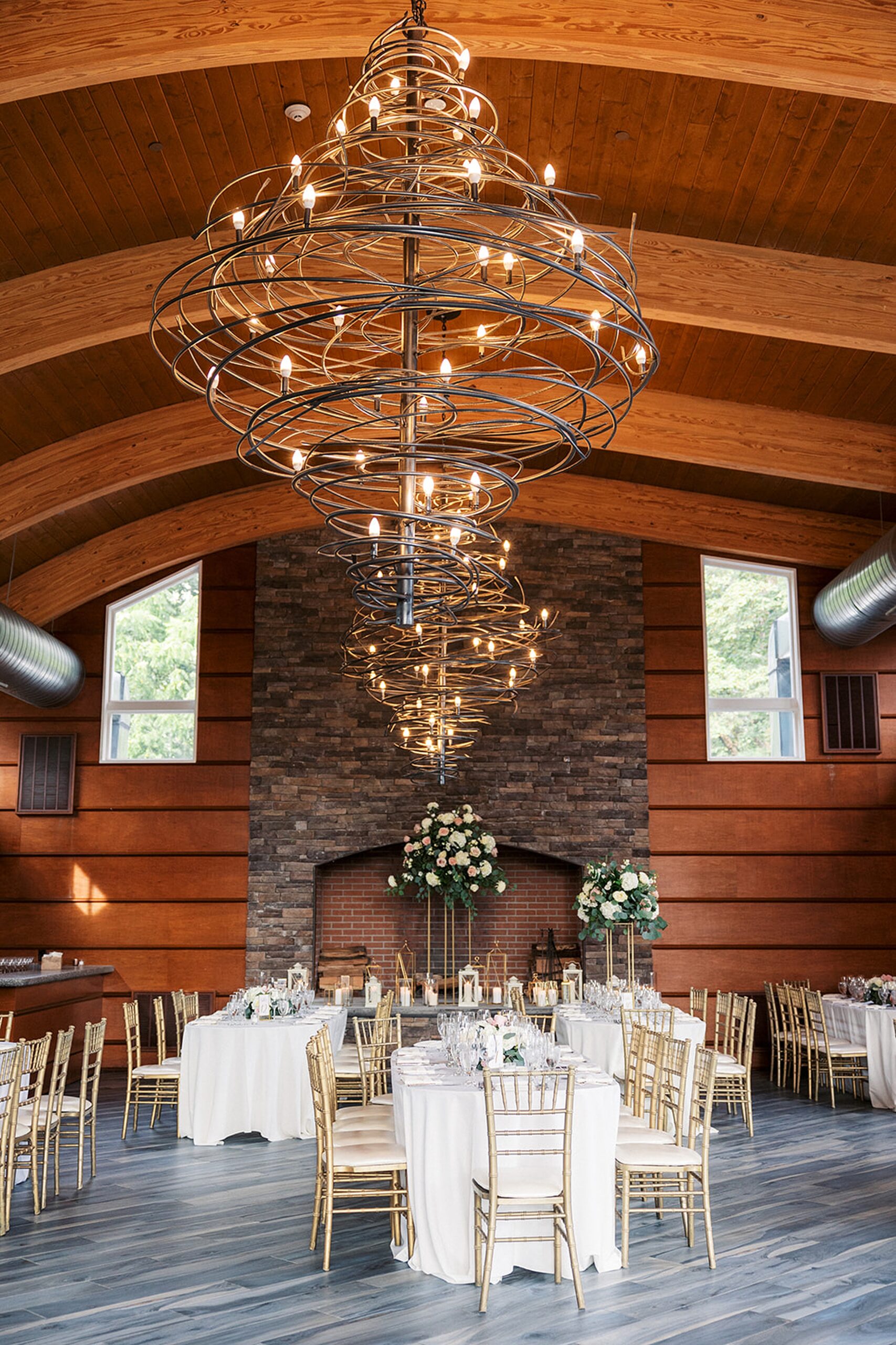Details of a Stonehouse At Stirling Ridge Wedding reception set up with modern chandeliers and a large stone fireplace