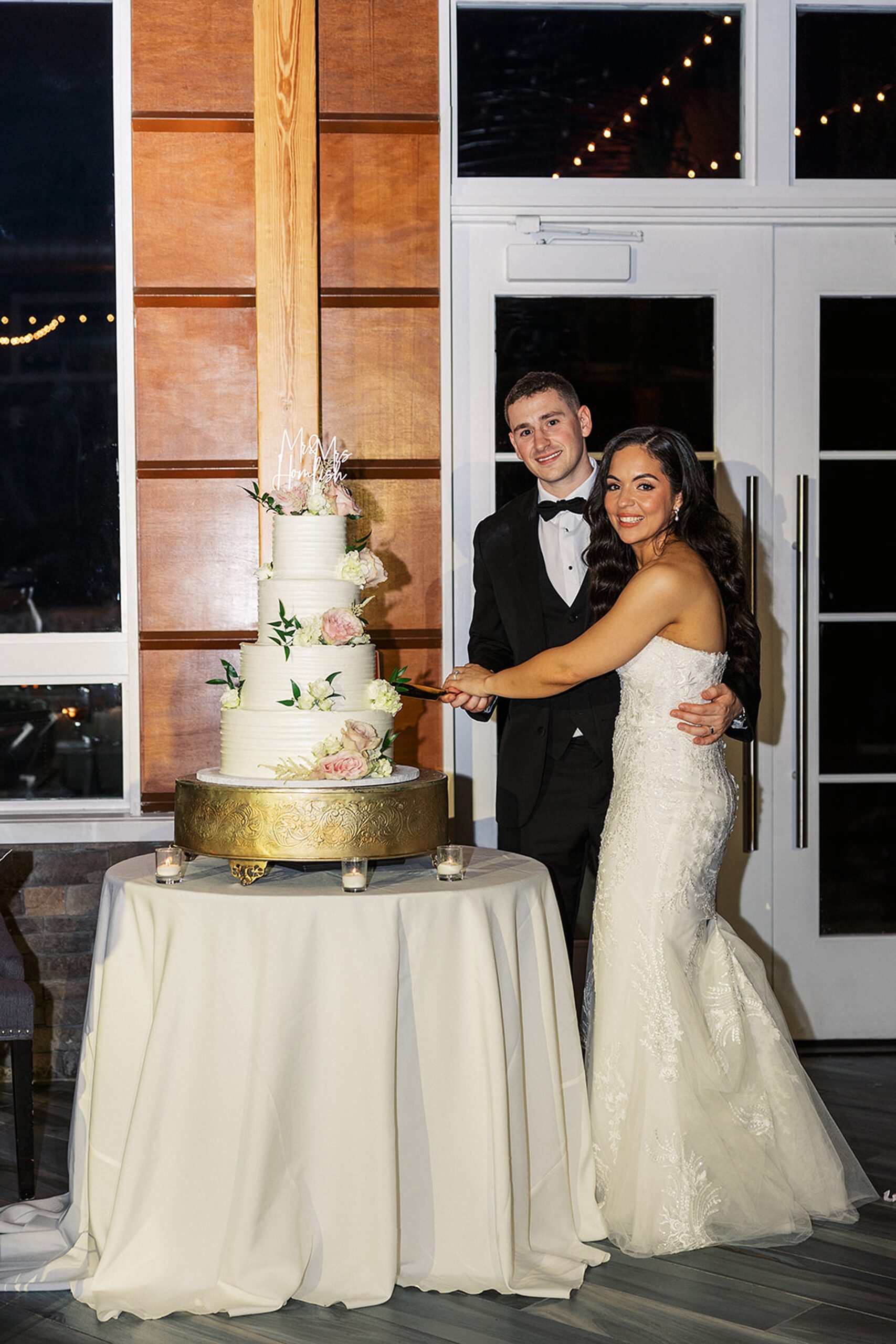 Newlyweds cut the cake covered in flowers at their Stonehouse At Stirling Ridge Wedding