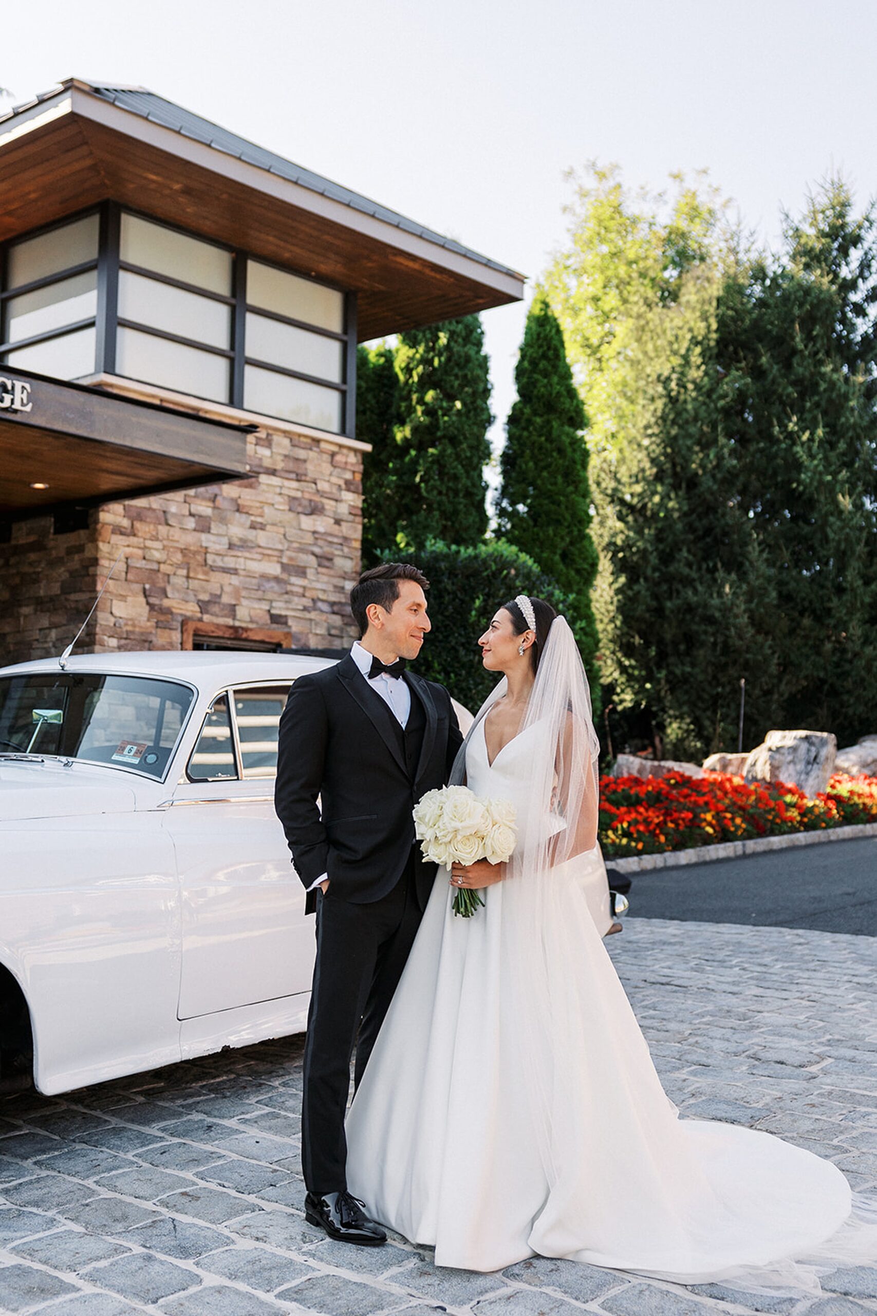 Newlyweds stand by a Rolls Royce limo in the garden of the Stonehouse At Stirling Ridge Wedding venue