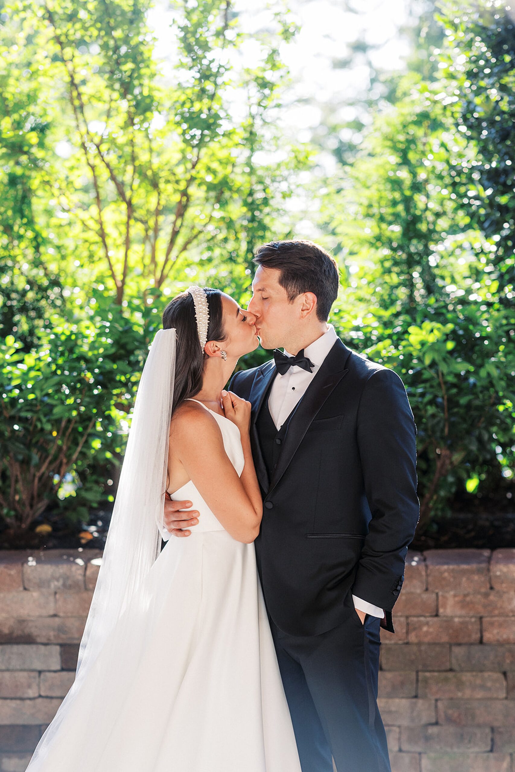 Newlyweds kiss in the gardens by a stone wall at the Stonehouse At Stirling Ridge Wedding venue