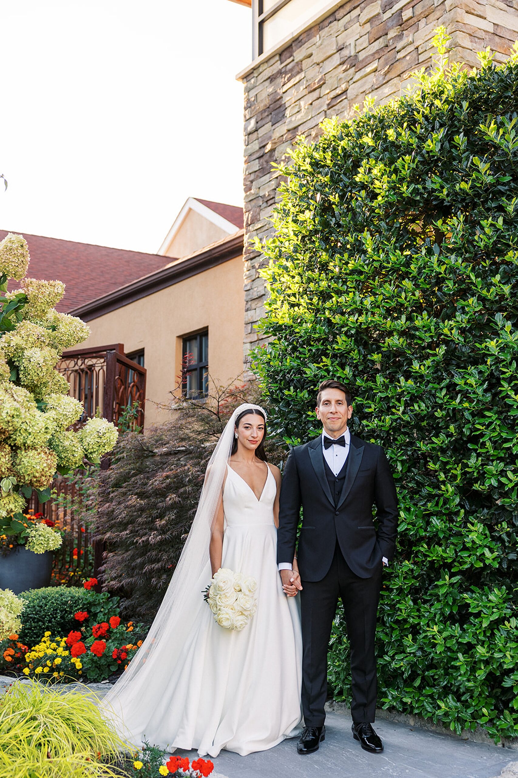 Newlyweds stand together in the garden behind the Stonehouse At Stirling Ridge Wedding venue
