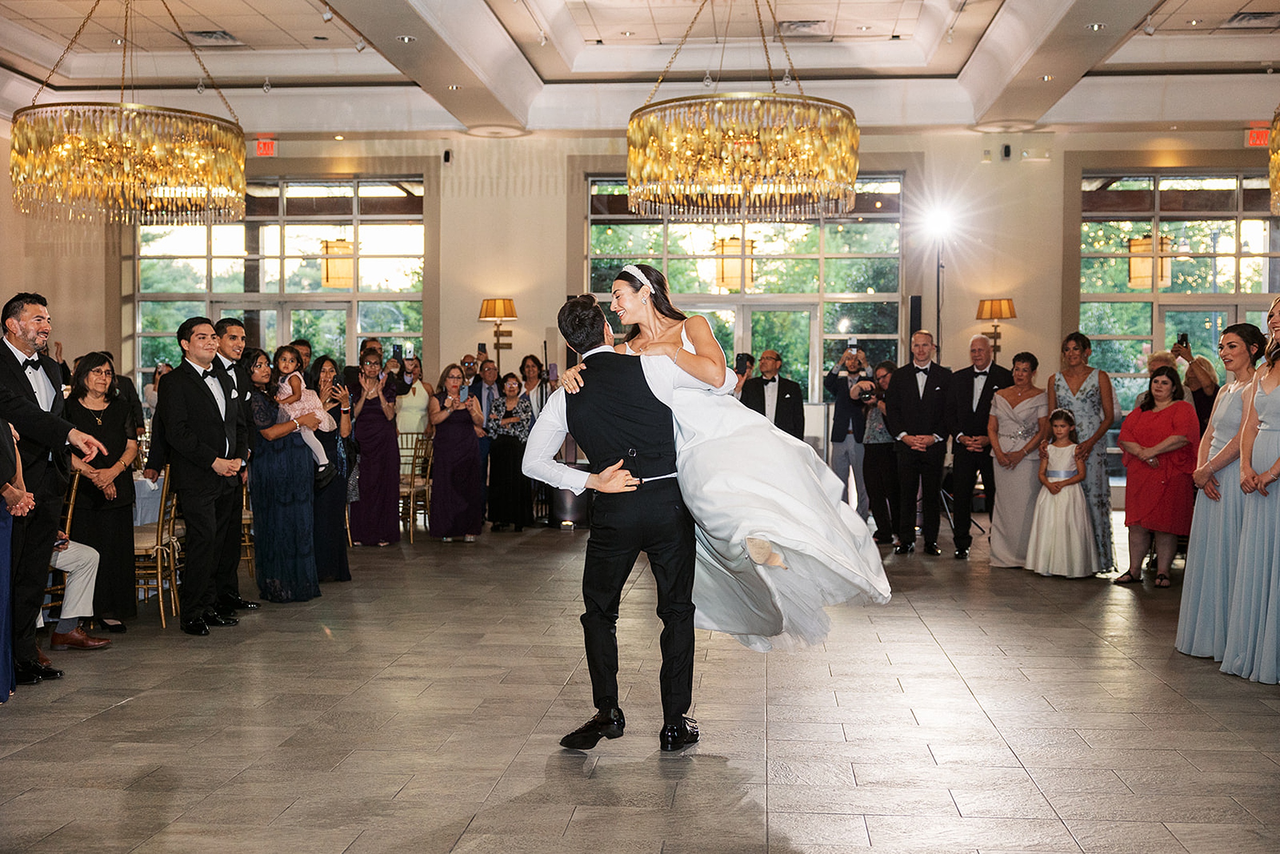 A groom swings his bride around the dance floor surrounded by guests at their Stonehouse At Stirling Ridge Wedding