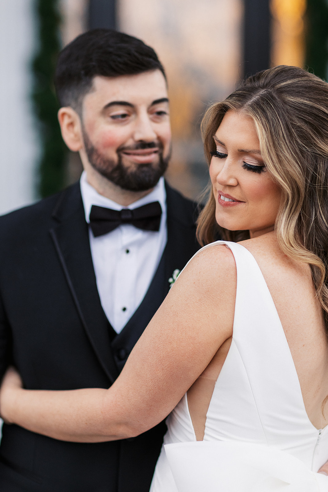 Newlyweds dance in a black tux and white silk dress outside