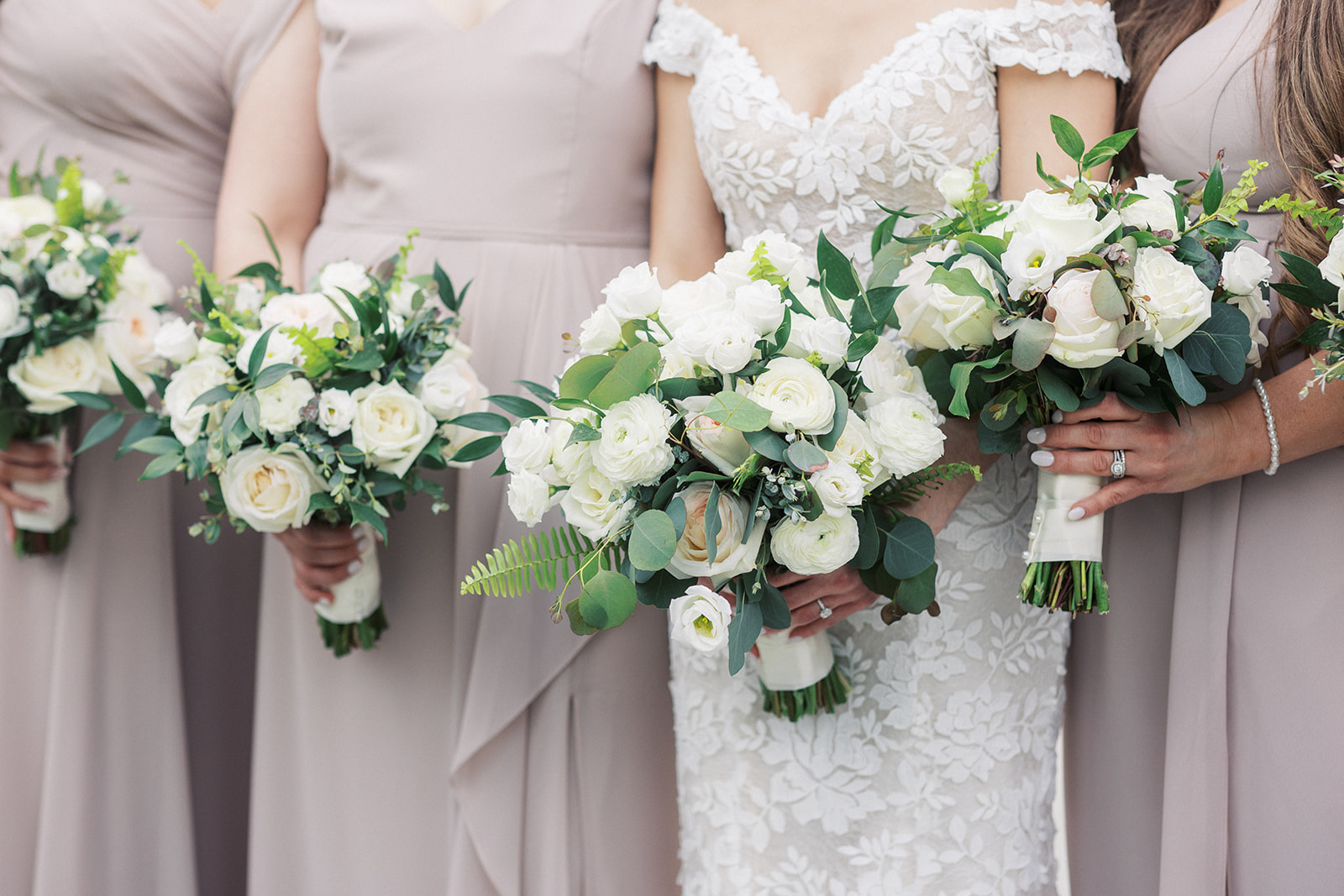 Details of a bride standing with her bridesmaids holding white rose bouquets at a Florentine Gardens Wedding