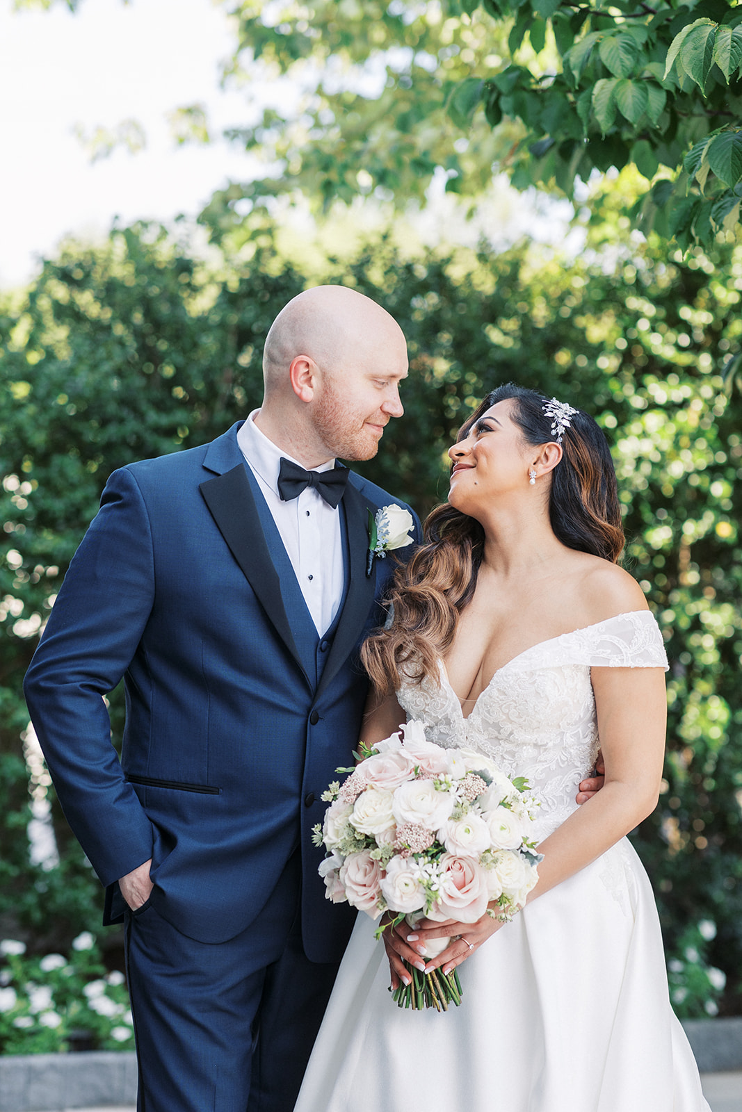 Newlyweds smile at each other while standing in a garden at an Old Tappan Manor Wedding