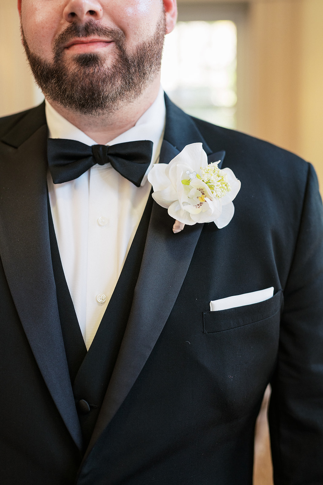 Details of a groom's white boutonniere on his black tuxedo jacket at a Park Avenue Club Wedding