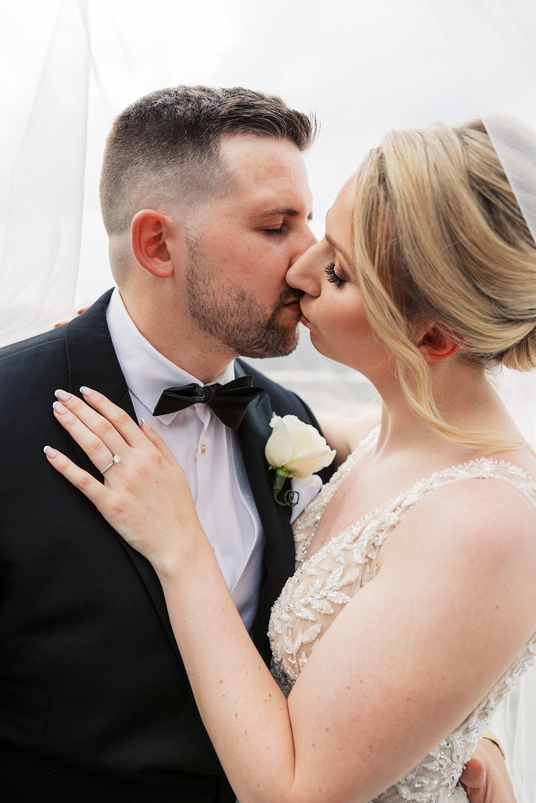 Newlyweds kiss under a veil while standing at a Richfield Regency Wedding