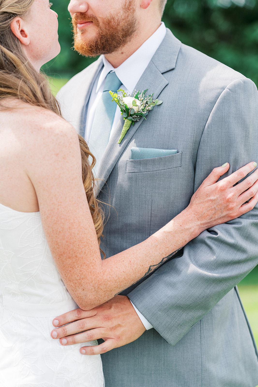 Details of a groom's grey suit as he dances with his bride