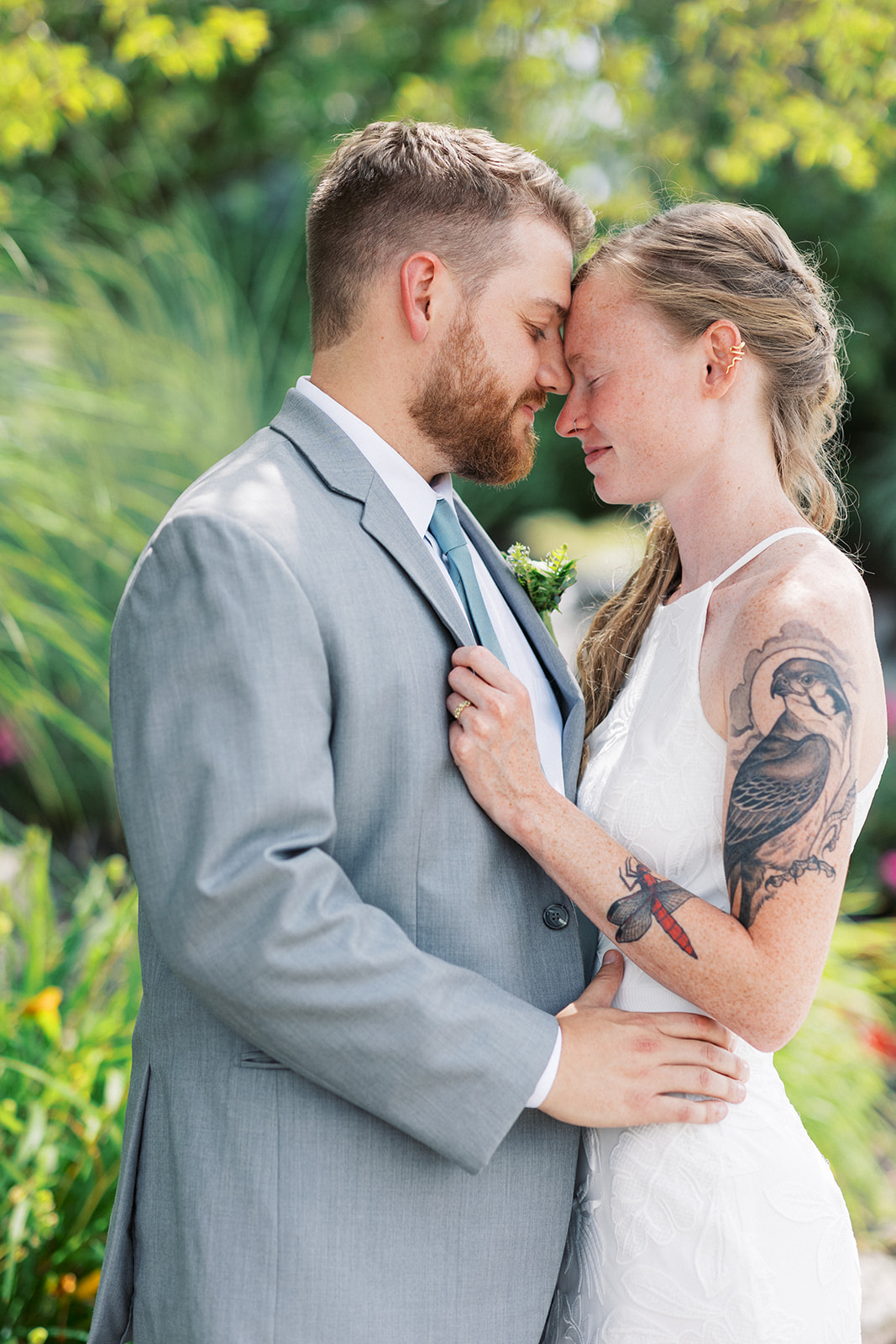 Newlyweds hold each other close while nuzzling foreheads in a garden at a Taylor Butler House Wedding