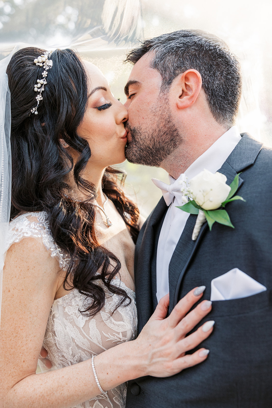 Newlyweds kiss while hiding under the long veil at their The Atelier Ballroom Wedding