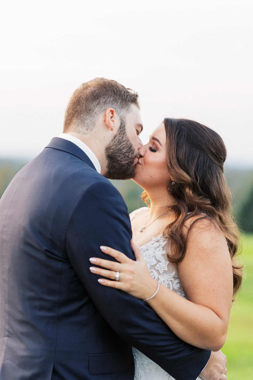 Newlyweds kiss while standing in a grassy lawn at sunset at The Mountain Lakes House Wedding