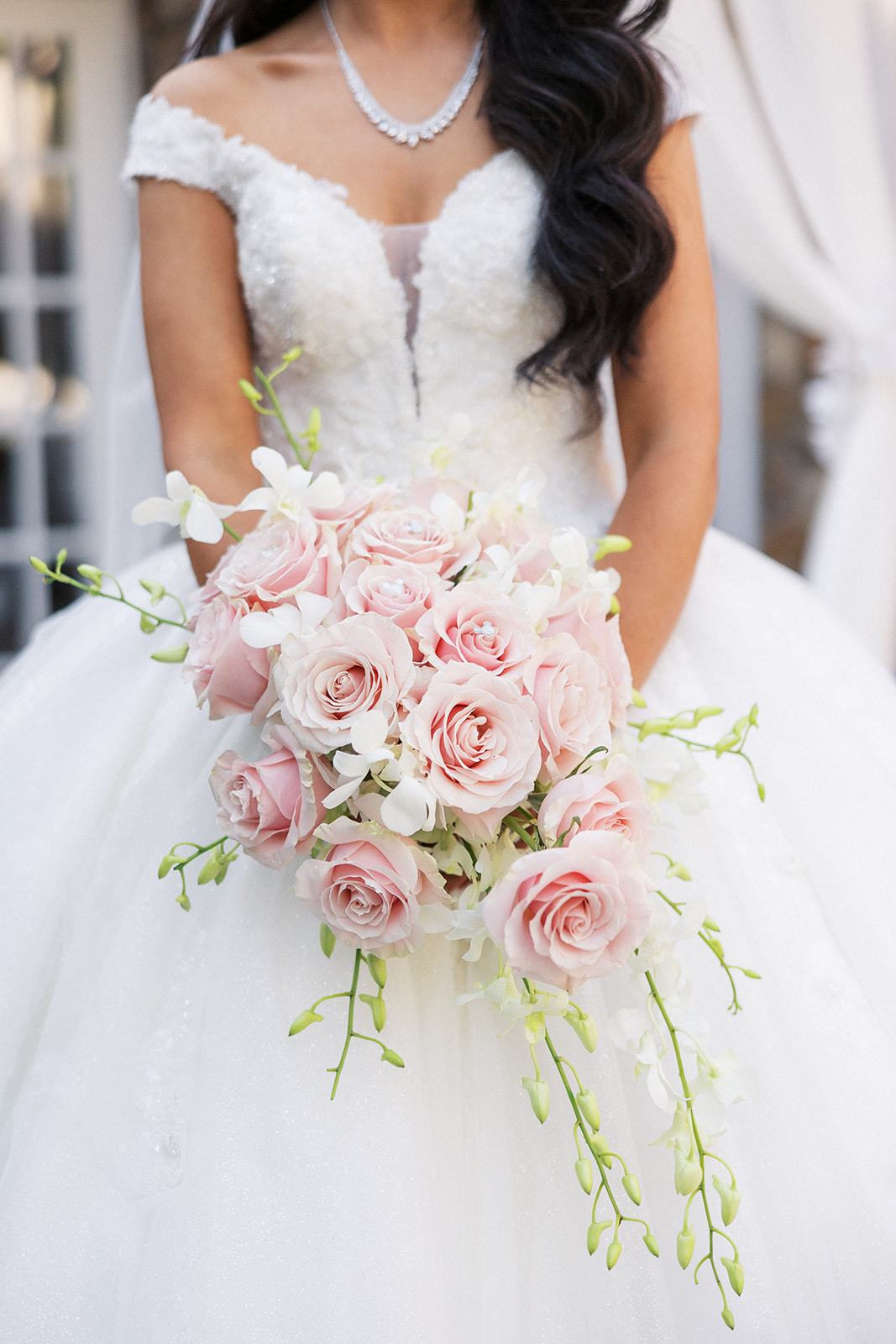 A bride holds her pink rose bouquet in front of her at The Tides Estate Wedding venue