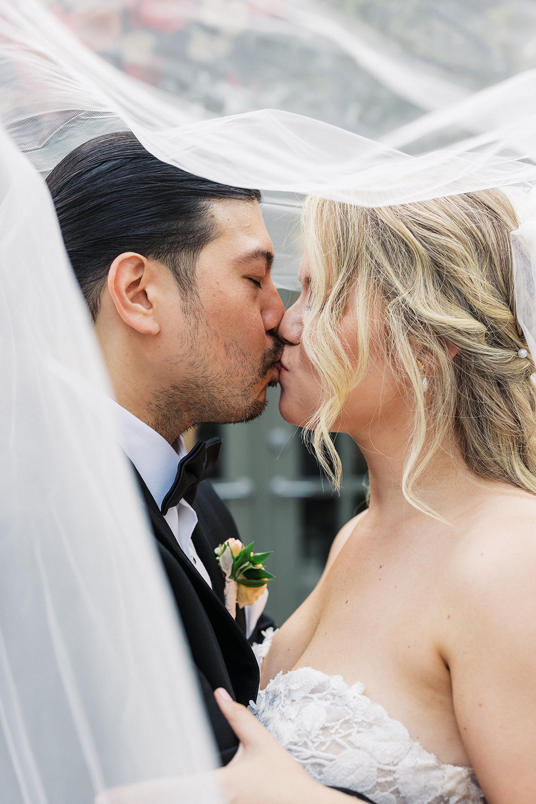Newlyweds kiss while hiding under a large veil at The Venetian Wedding venue