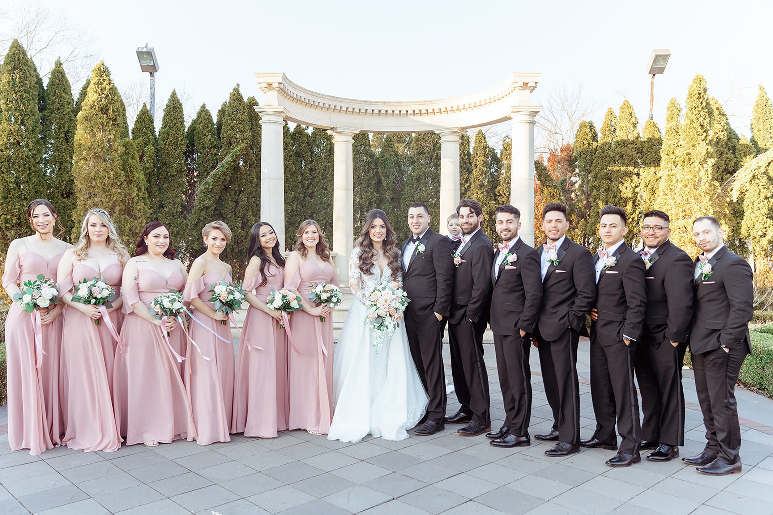 Newlyweds stand together in a garden patio with their wedding party surrounding them