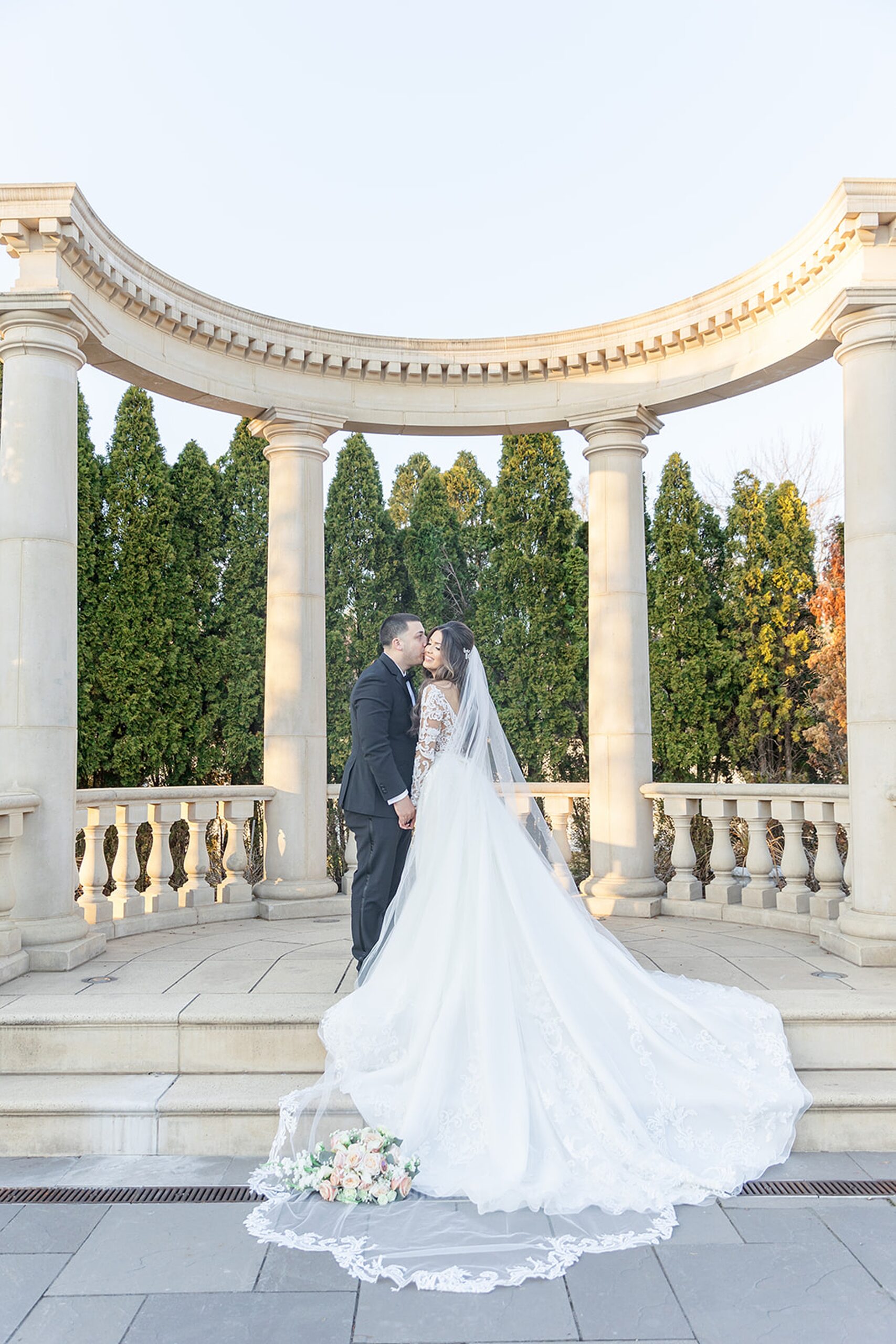 Newlyweds kiss while standing among a column gazebo at the rockleigh wedding venue