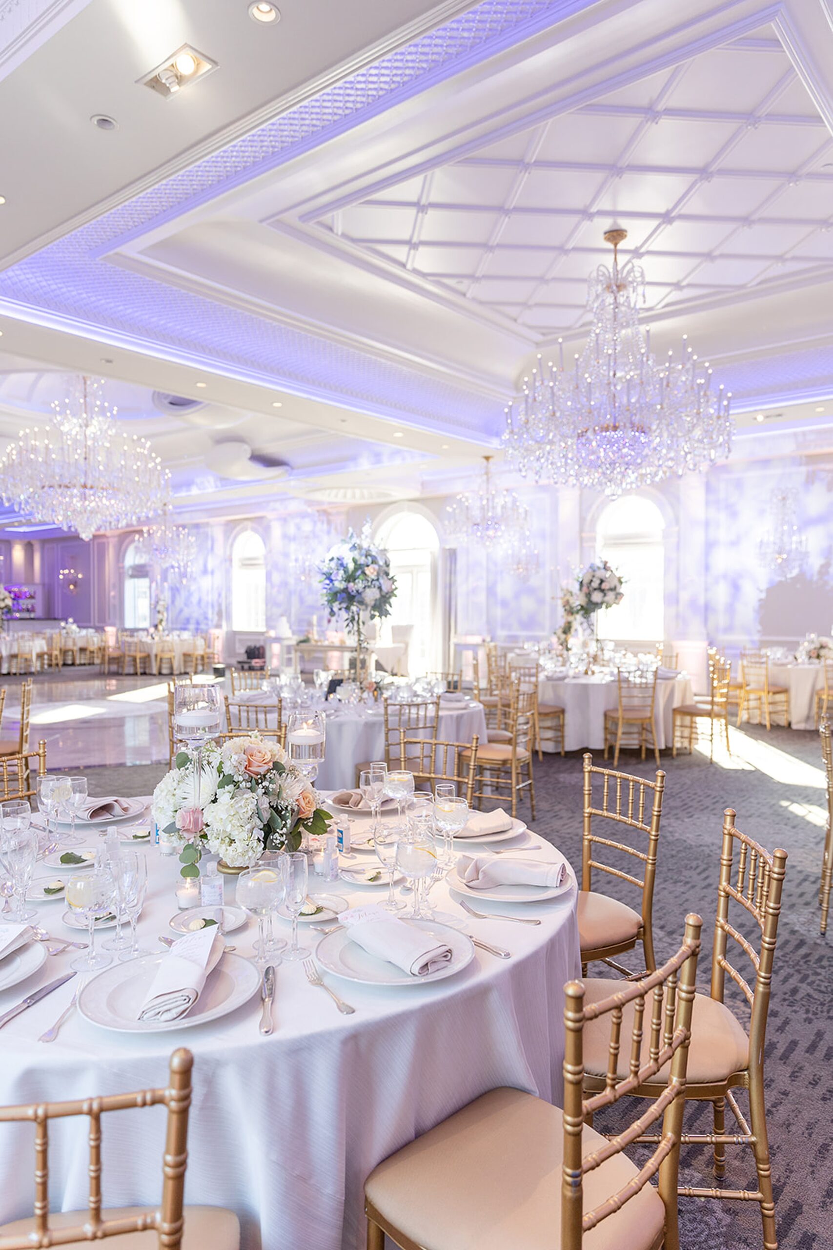 Details of a wedding reception ballroom setup with white linen and gold chairs at the rockleigh wedding venue