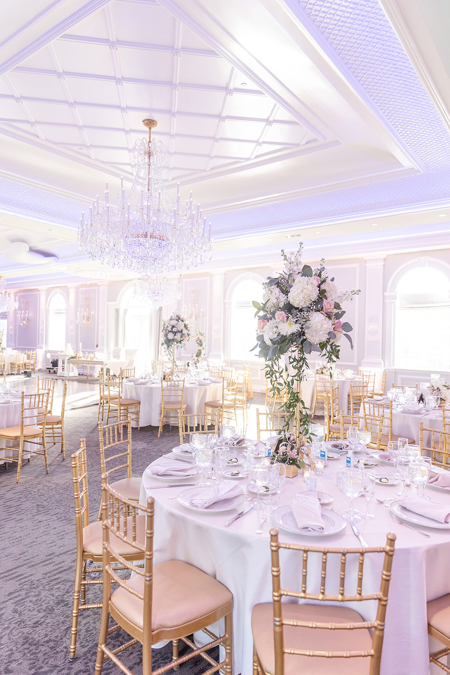 Details of a luxury ballroom wedding reception with many windows and gold chairs